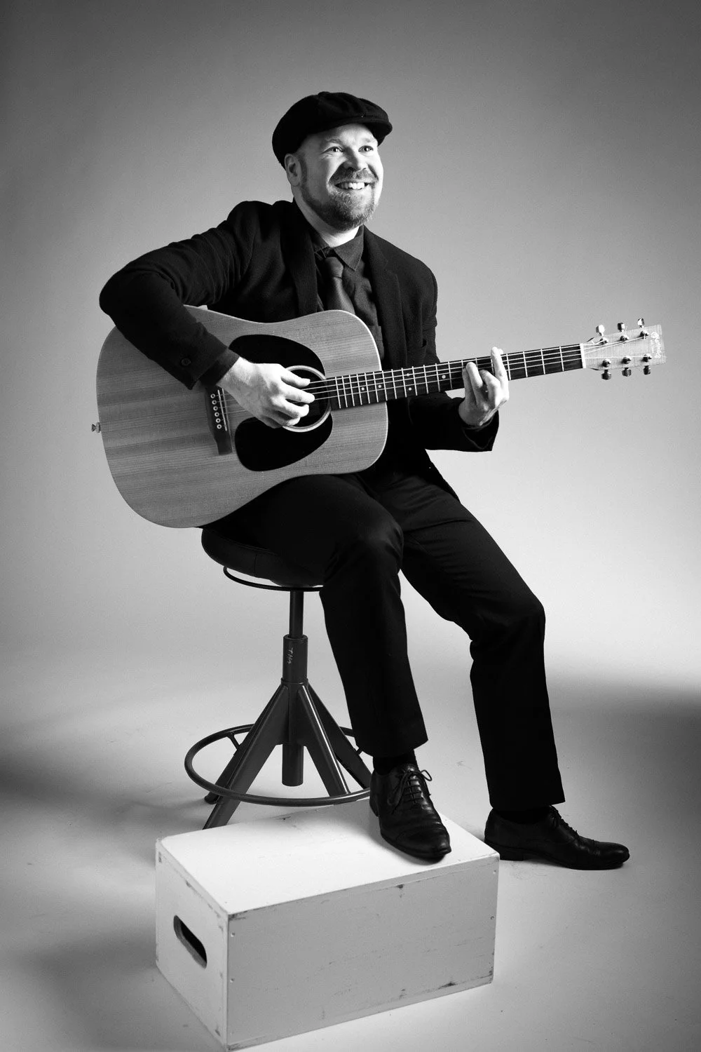 Potretti studiossa, mies soittaa kitaraa, mustavalkokuva