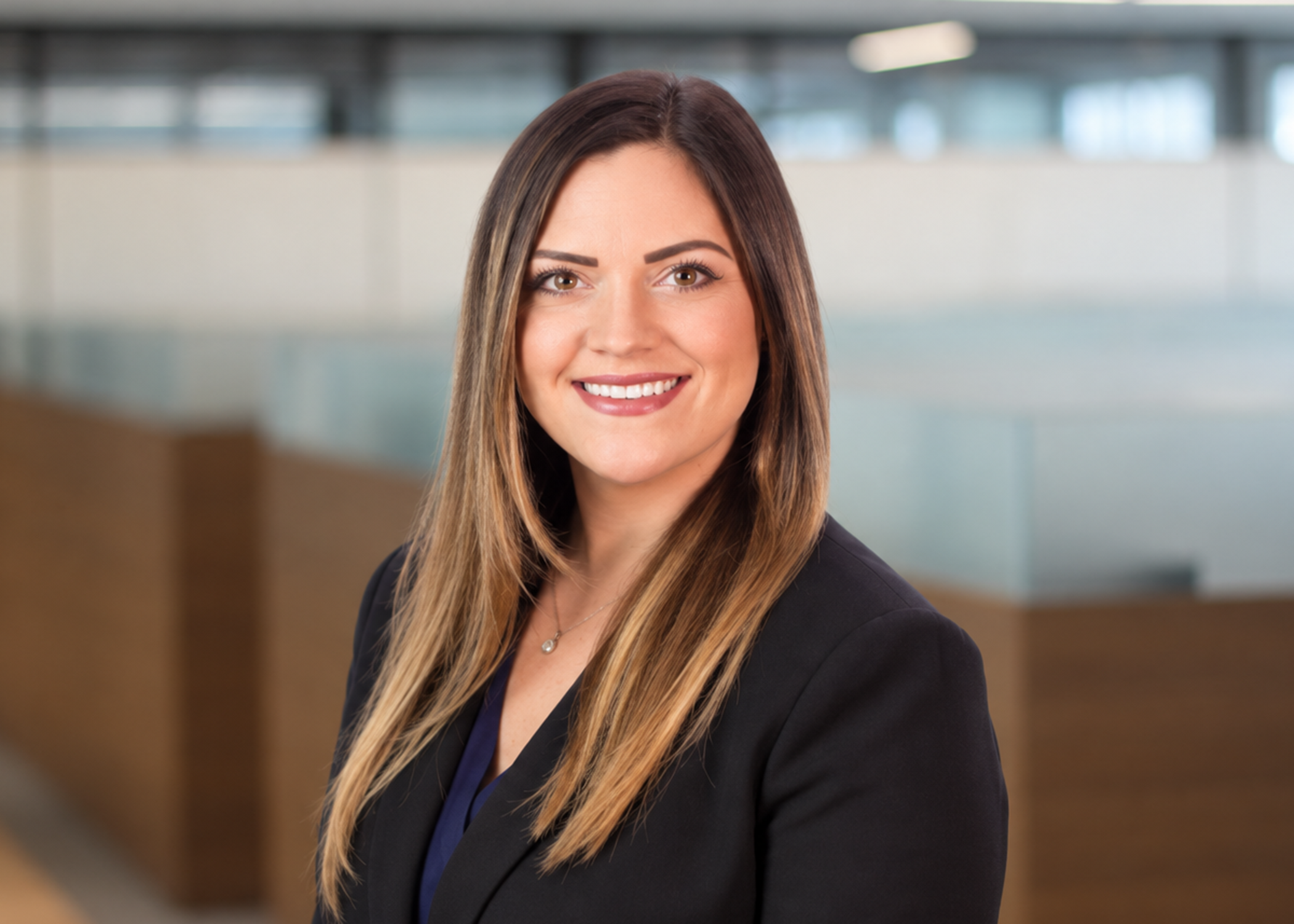 A woman in a professional setting with brown hair smiling.