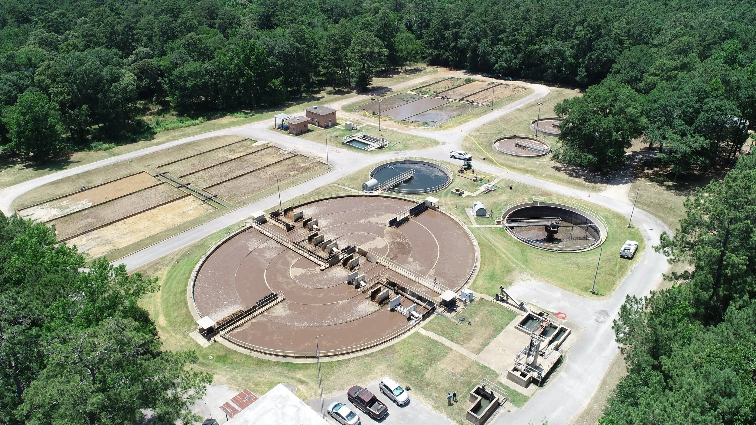 An arial view of a wastewater treament plant, surrounded by green foliage
