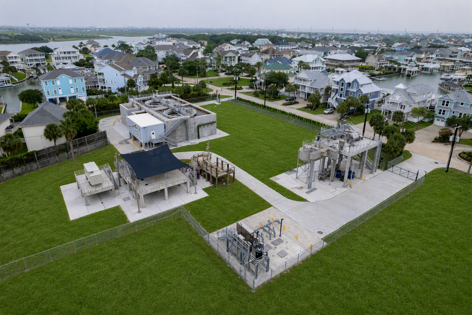 An arial view of a wastewater treatment plant, surrounded by green grass and beach houses