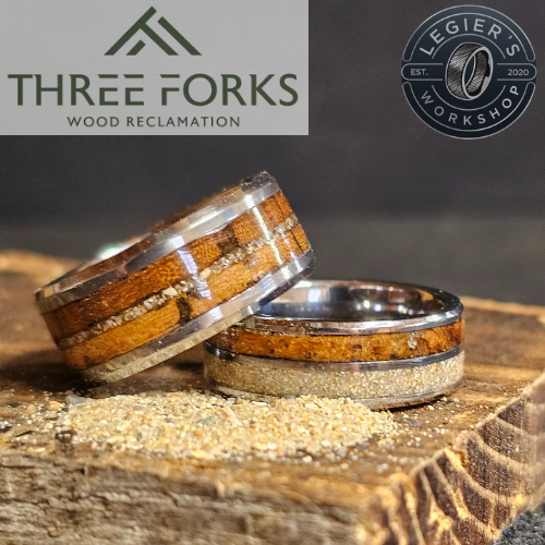 Two rings made with Omaha Beach and Utah Beach barnwood, as well as beach sand from Omaha and Utah Beach. Logos for Three Forks Wood Reclamation and Legier's Workshop are in the background.
