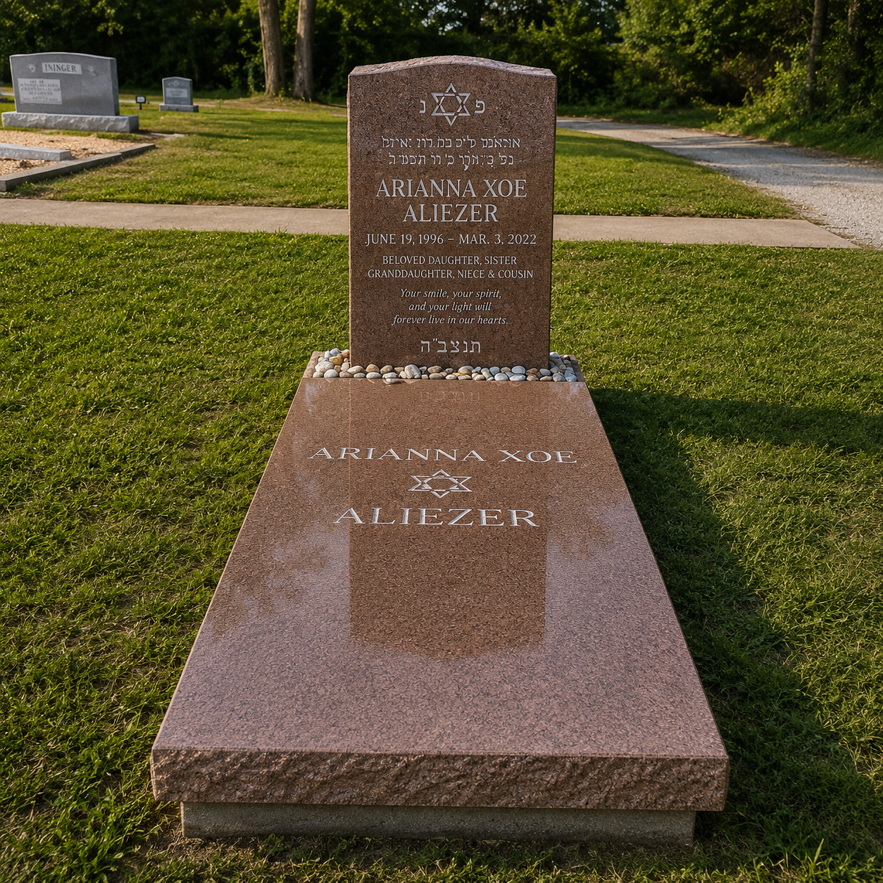 A red granite headstone in a cemetery with a Star of David at the top, inscribed with the name Arianna Xoe Aliezer, dates June 19, 1996, to March 3, 2022, and an inscription in English and Hebrew honoring her as a beloved daughter, sister, granddaughter, niece, and cousin.