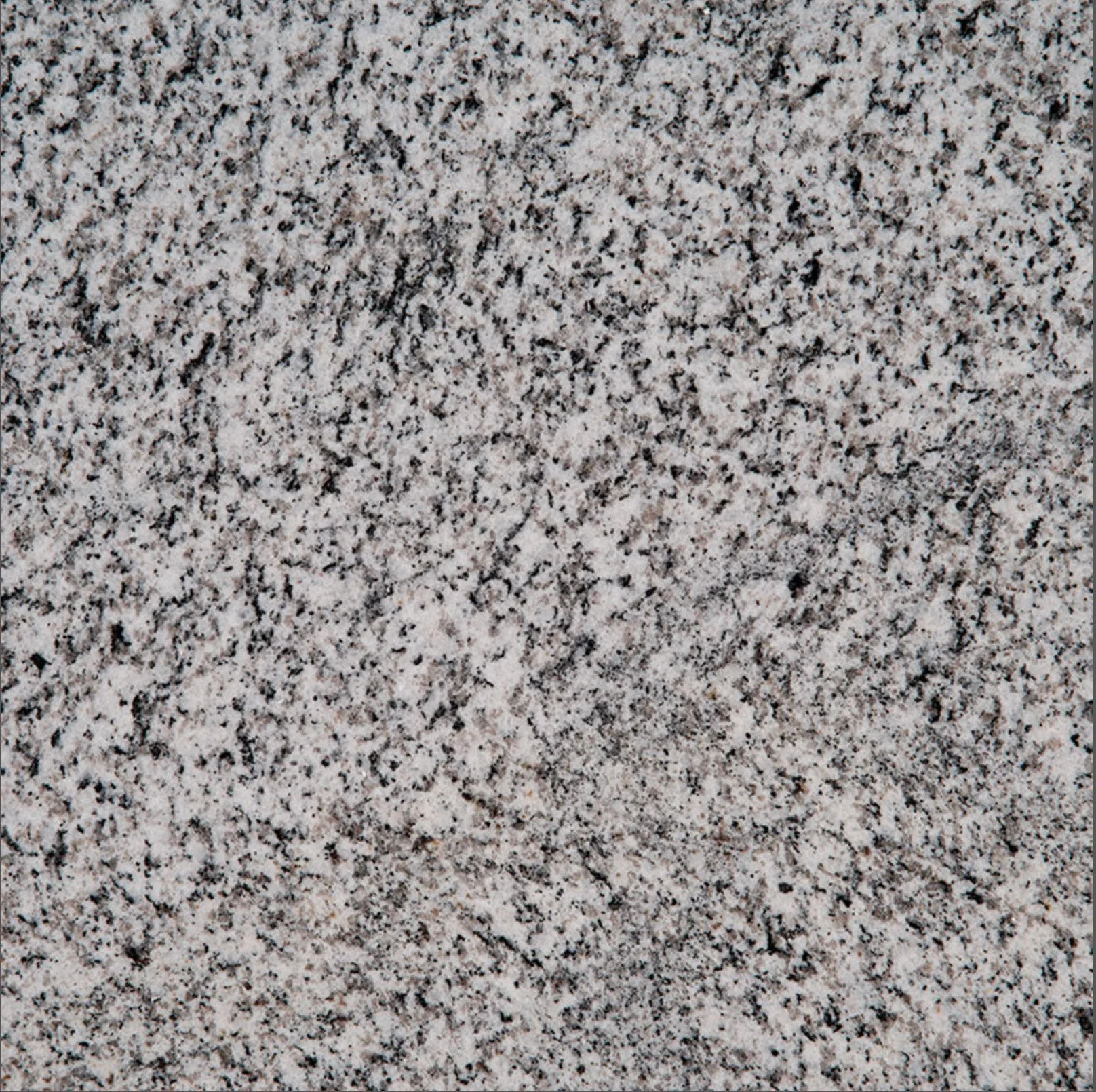 Close-up of speckled granite surface with black, white, and pinkish mineral grains.