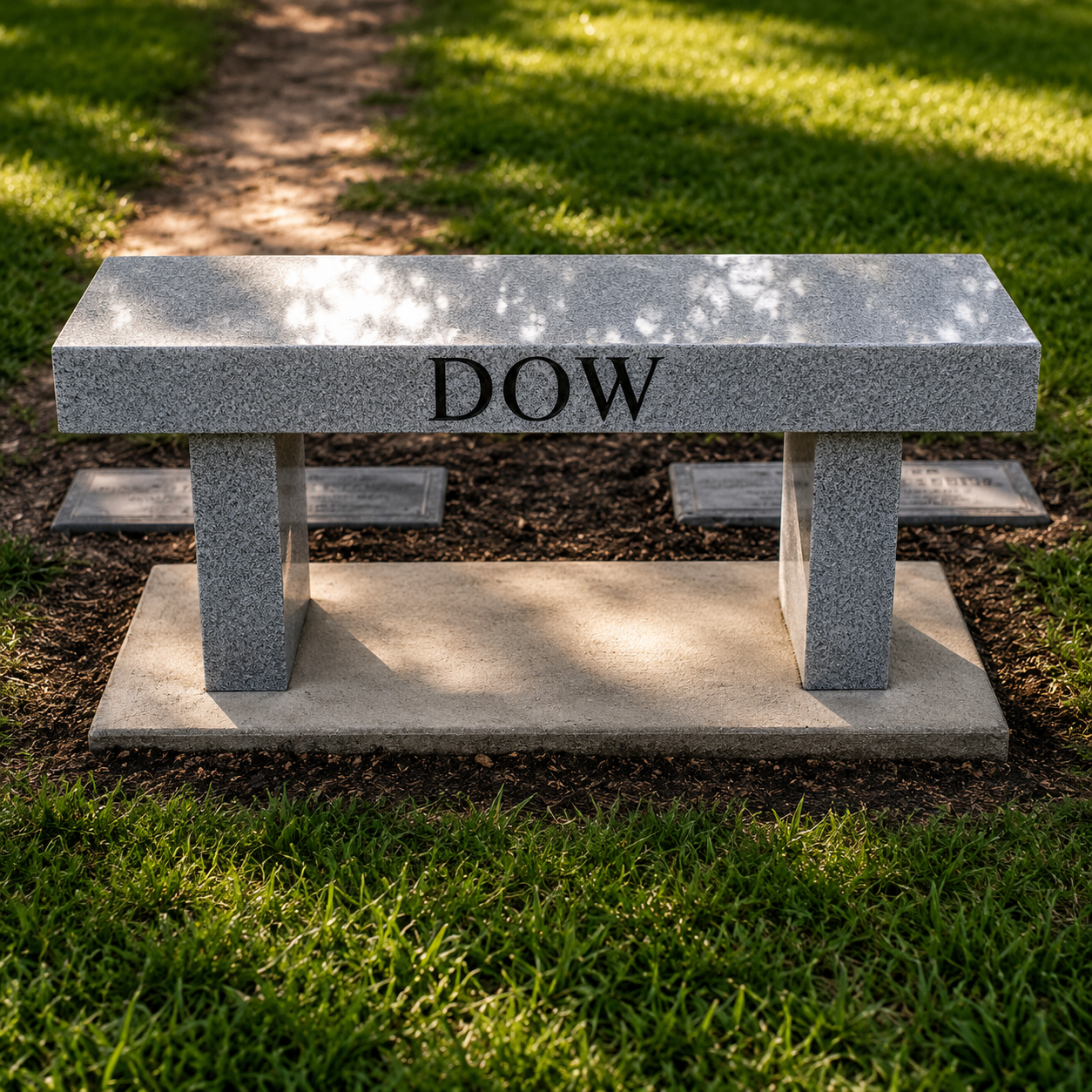 Stone bench with the word 'DOW' engraved on it, situated on grass with a dirt pathway behind it.