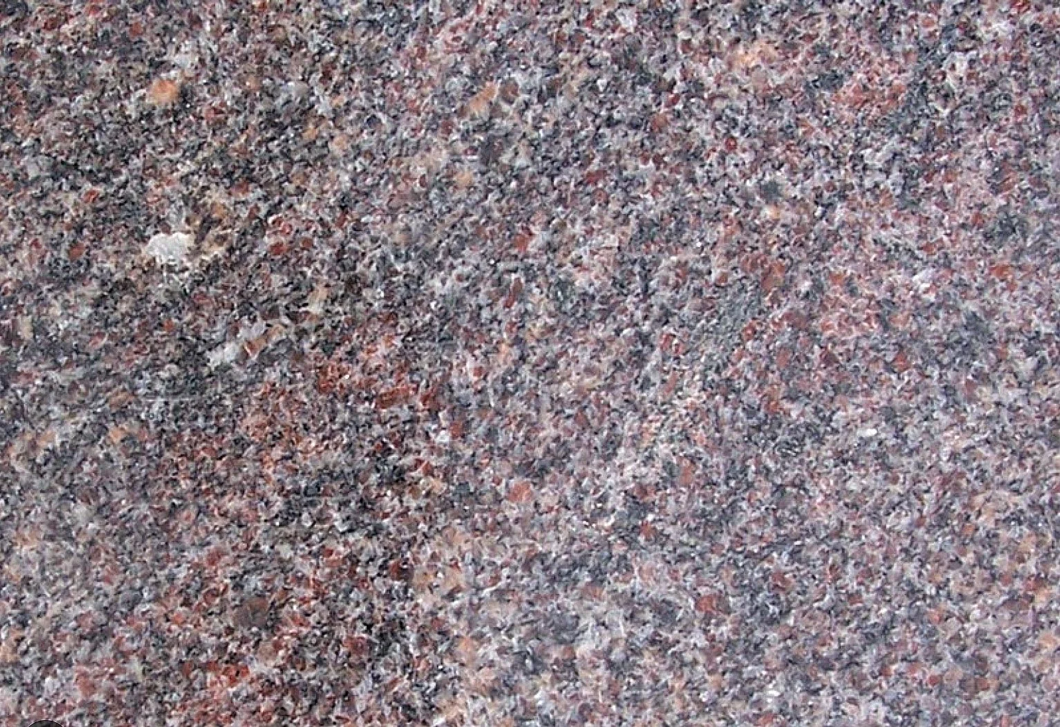 Close-up image of a granite surface with a mixture of pink, gray, black, and white mineral grains.