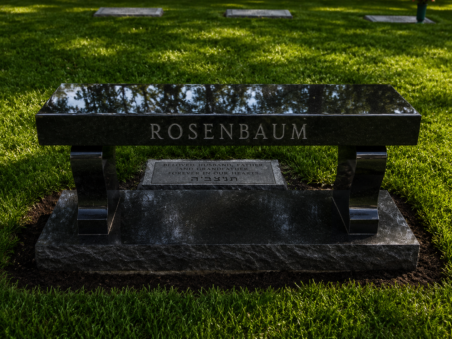 A black granite memorial bench with the name 'Rosenbaum' engraved on the top, located in a grassy cemetery with some headstones visible in the background.