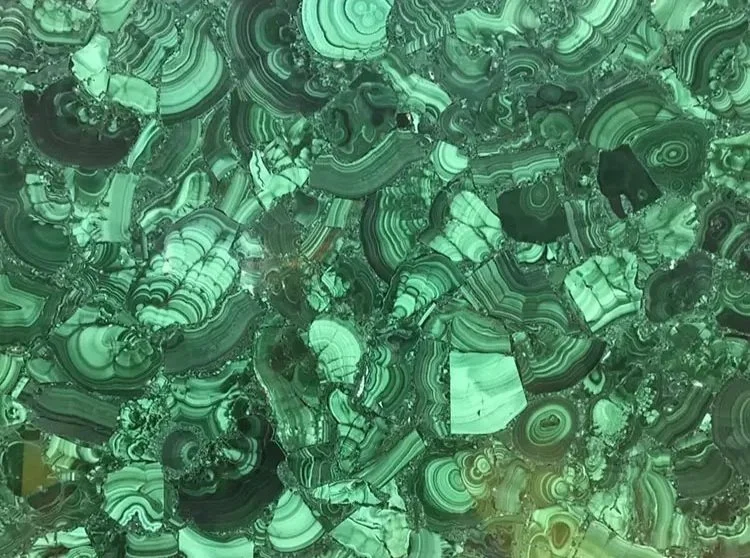 Close-up image of green malachite gemstone with intricate banding and swirling patterns.