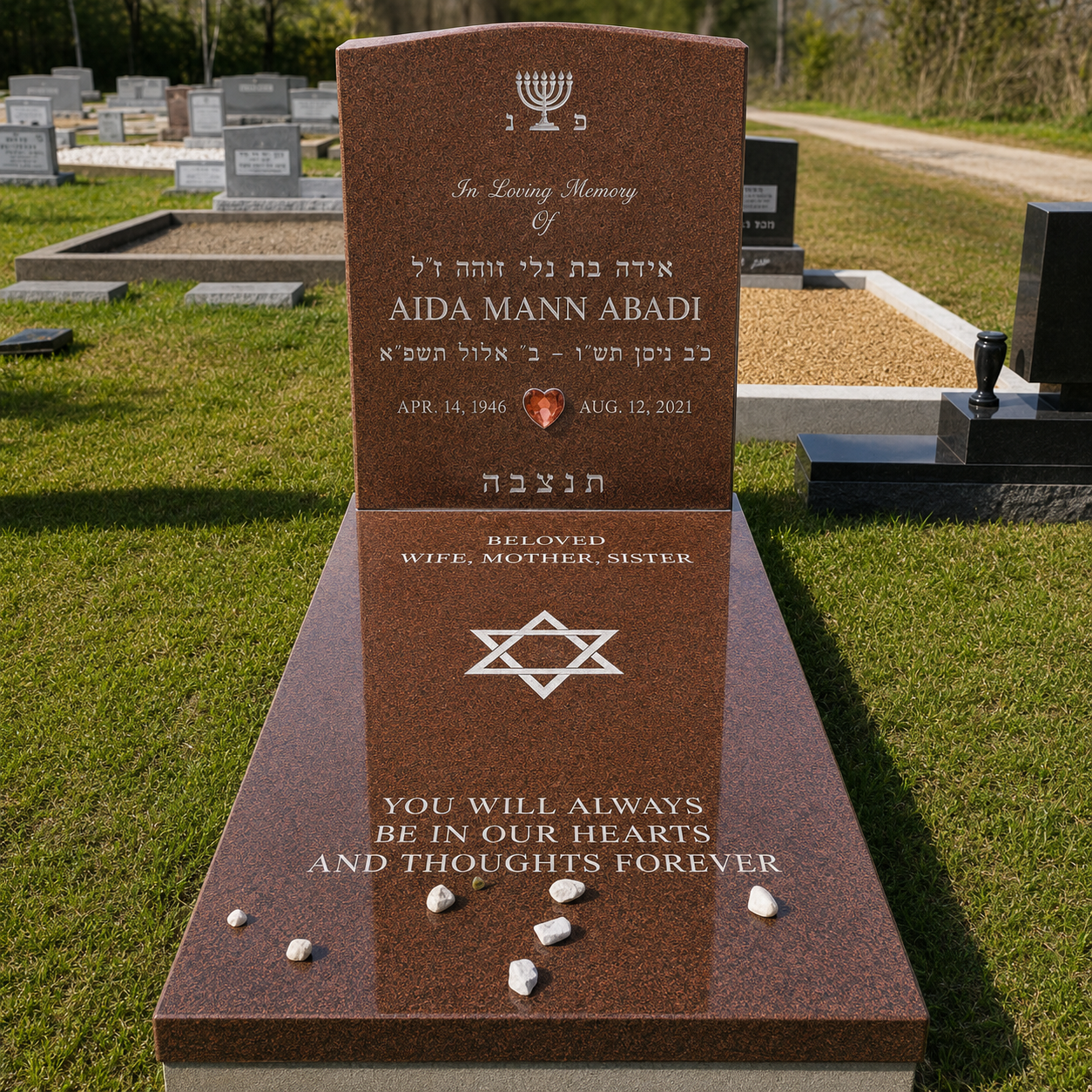 Gravestone in a cemetery with inscriptions in English and Hebrew, a menorah symbol, a red gemstone, and a Star of David, commemorating Aida Mann Abadi.