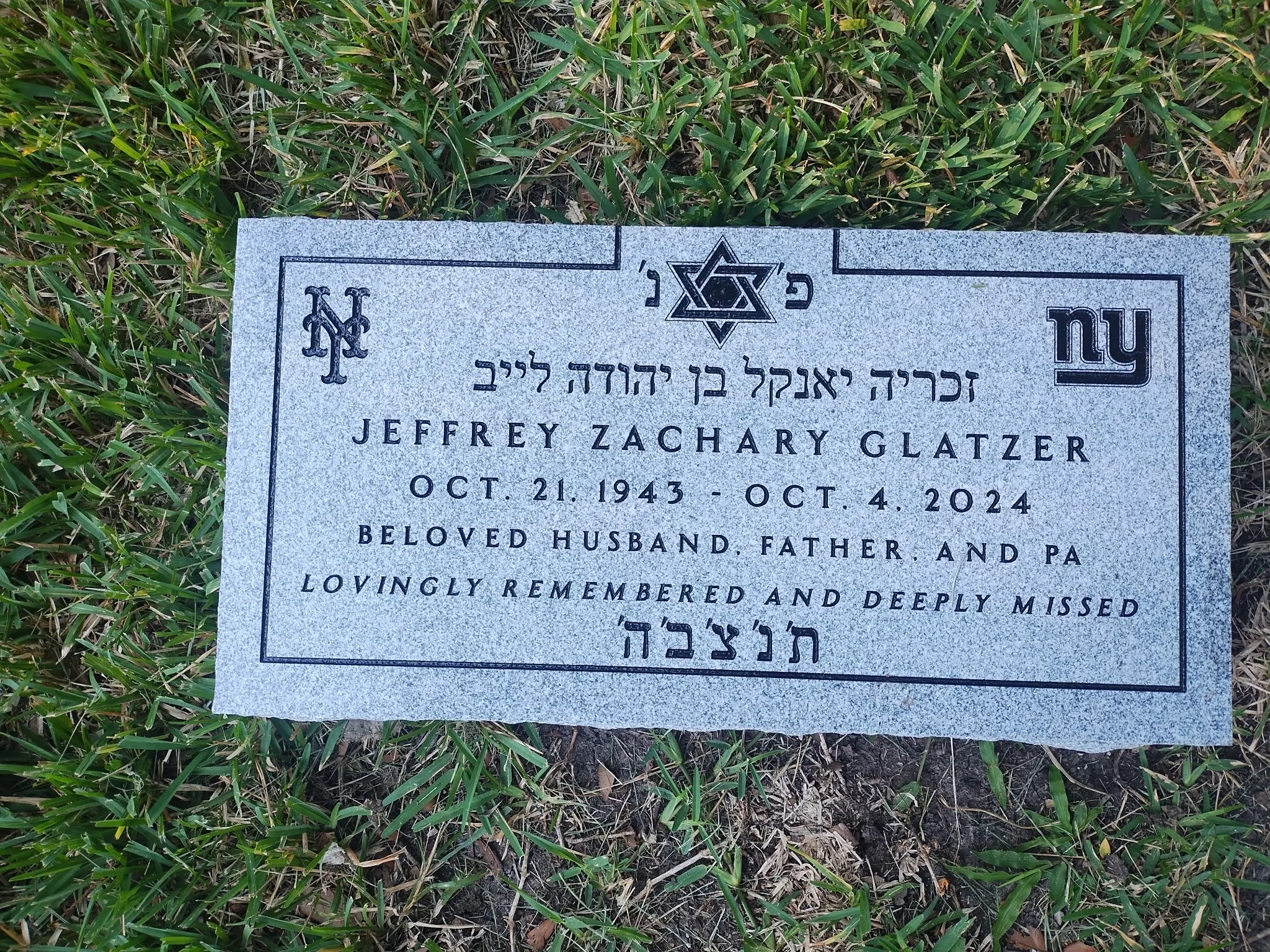 Gravestone for Jeffrey Zachary Glatzer with Hebrew and English inscriptions, surrounded by grass.