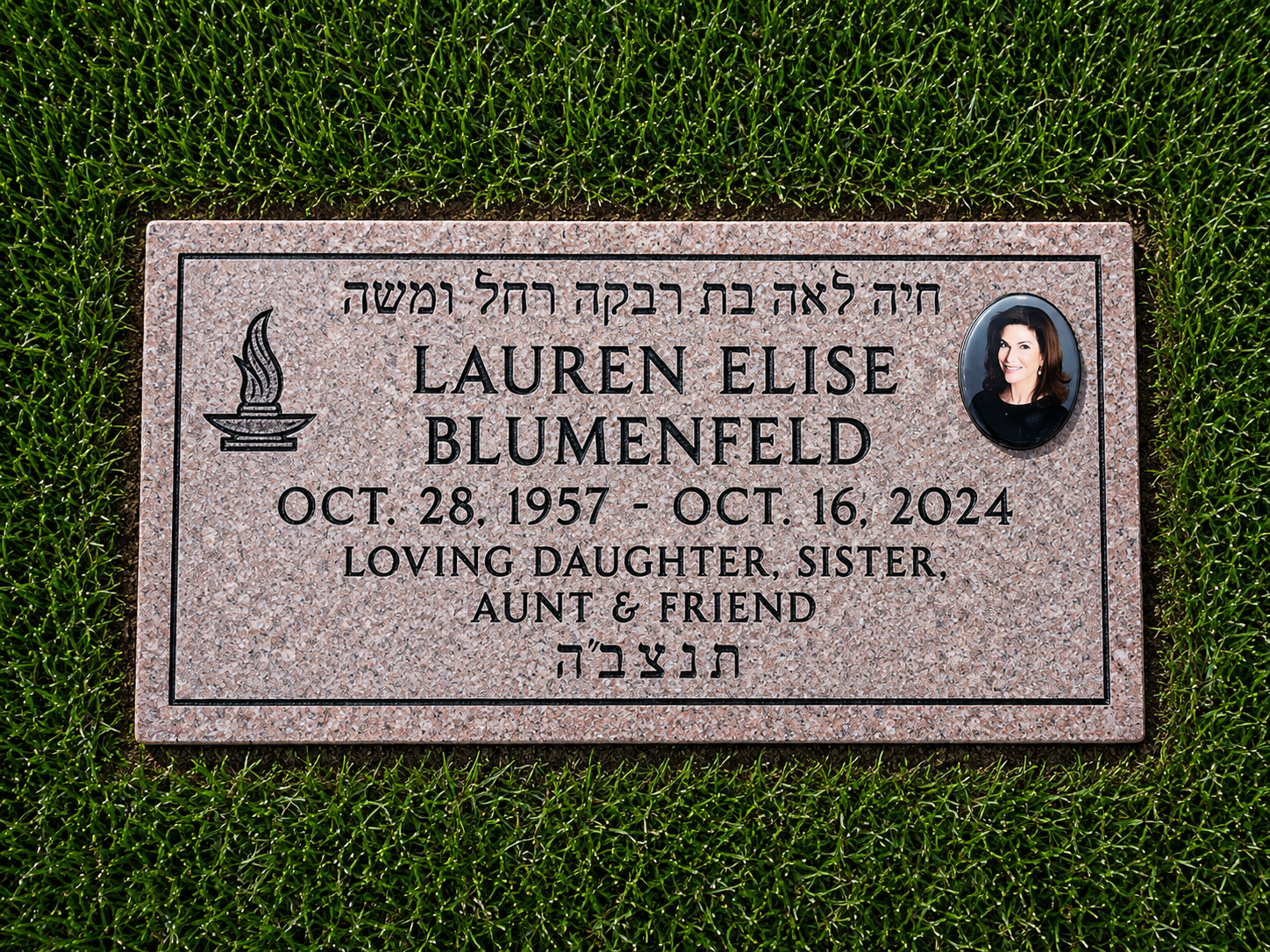 A granite grave marker with an oval portrait of a woman in the top right corner, black engraved lettering displaying the name Lauren Elise Blumenfeld, her birth and death dates, and descriptions including loving daughter, sister, aunt, and friend. The grave marker is set on grass.