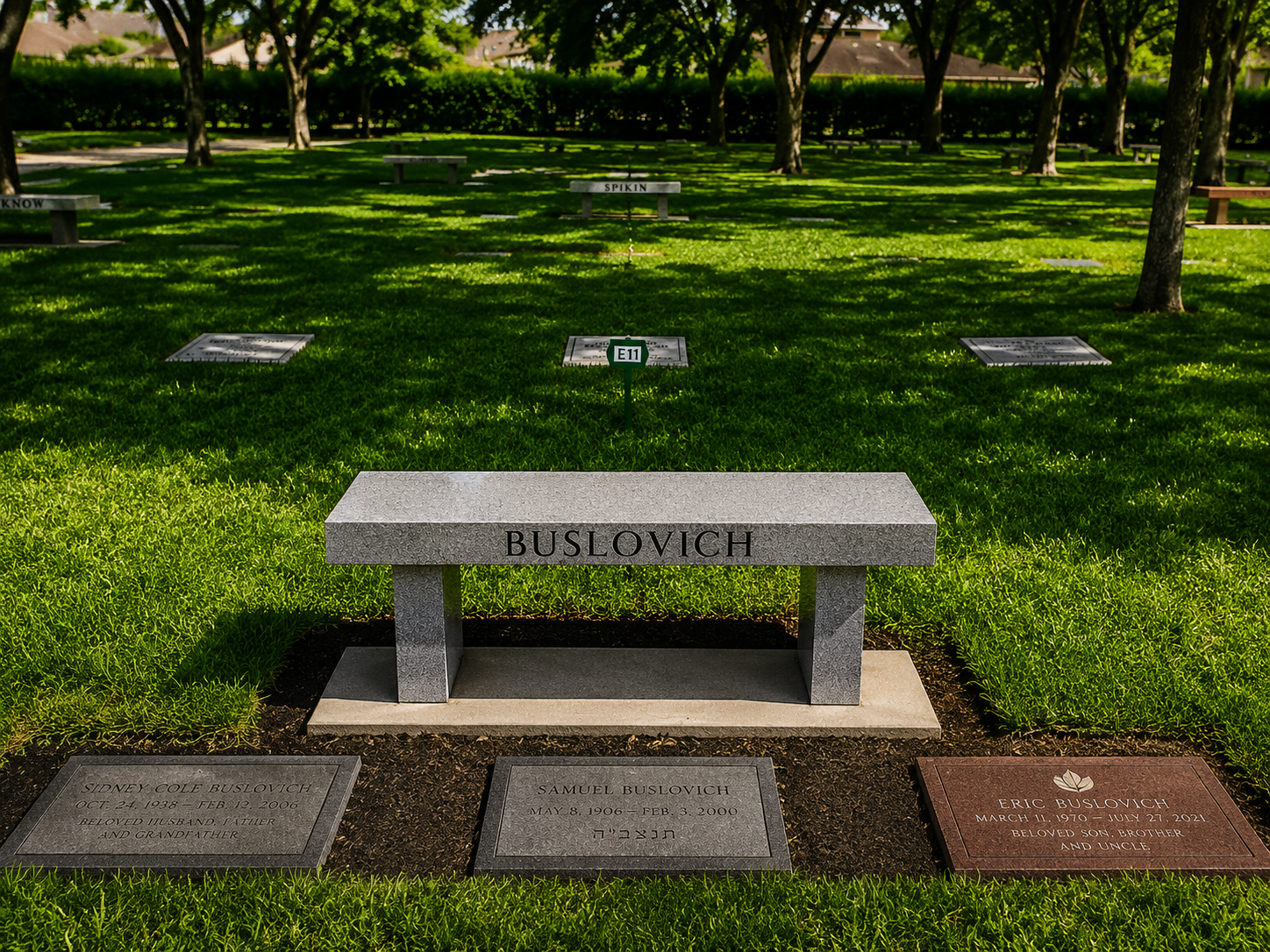 Grave of Sidney Cole Buslovich with a headstone, surrounded by other graves, with a lawn and trees in the background.