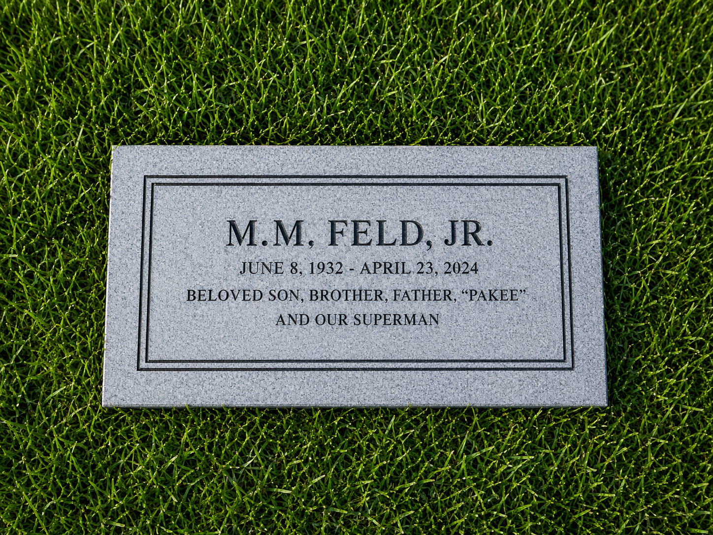 Gravestone for M.M. Feld Jr., with dates June 8, 1932, to April 23, 2024, on lush green grass.