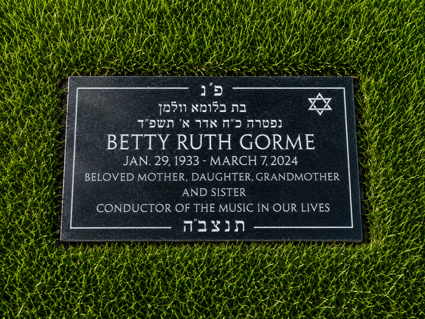 A black granite grave marker surrounded by green grass. It is dedicated to Betty Ruth Gorme, with dates of birth and death, and mentions she was a beloved mother, daughter, grandmother, sister, and conductor of music.