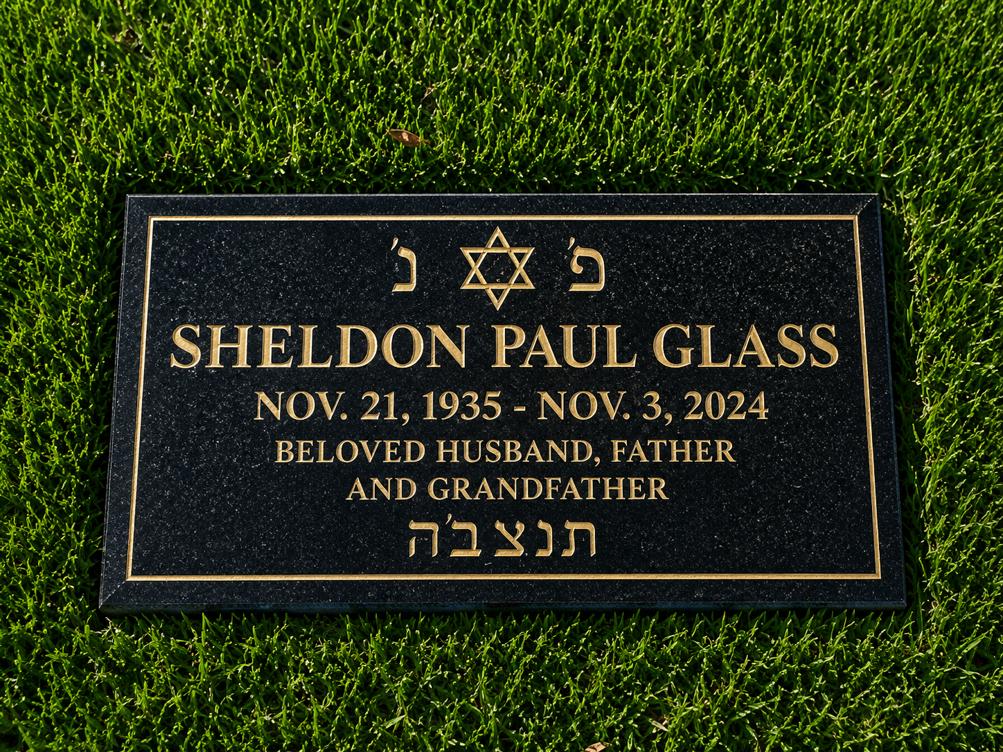 Gravestone with gold lettering for Sheldon Paul Glass, born November 21, 1935, died November 3, 2024, surrounded by green grass.