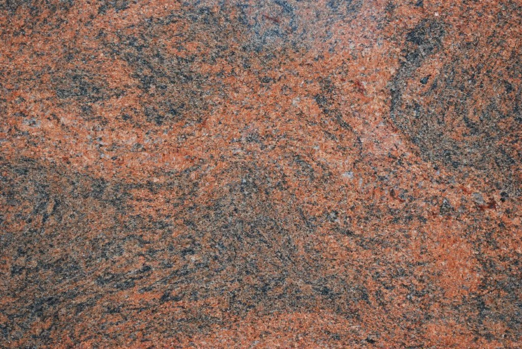 Close-up of a textured granite surface with a mix of red, black, and gray mineral patterns.