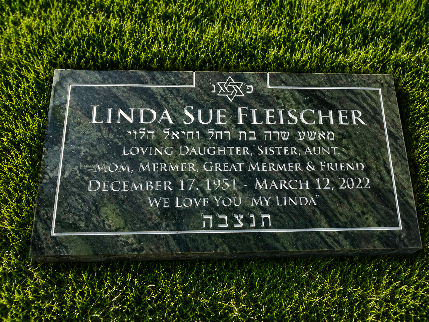Green marble grave marker for Linda Sue Fleischer with engraved text, a Star of David at the top, and Hebrew scripture.