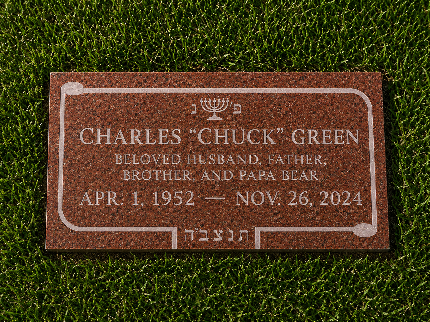Gravestone of Charles "Chuck" Green with a menorah symbol above his name, engraved on red granite, surrounded by green grass.