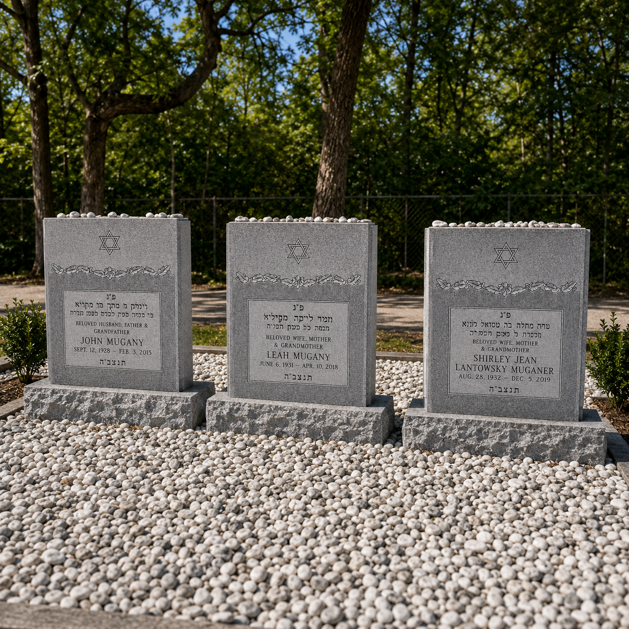 Three gray Jewish headstones in a cemetery, each with a Star of David and engraved Hebrew and English inscriptions, atop white pebbles with trees and a fence in the background.