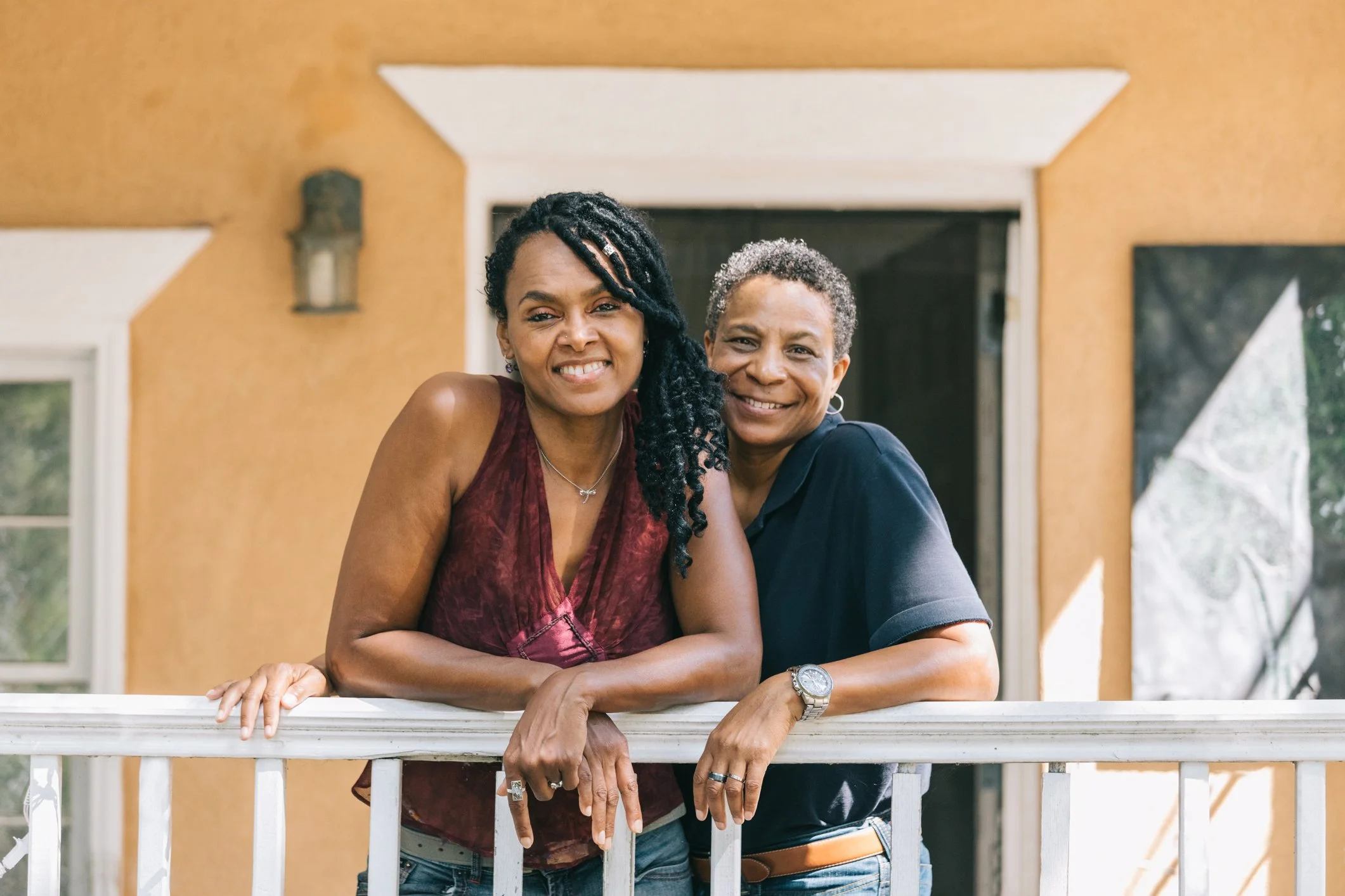 two women smiling in front of a house