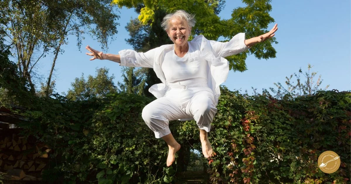A woman jumping joyfully in a garden