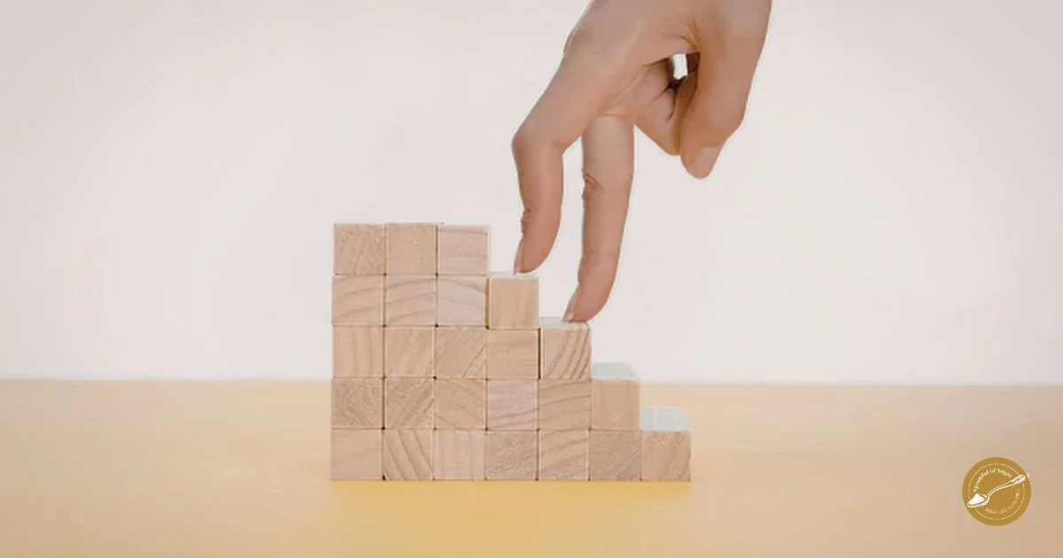 Fingers carefully climbing small wooden blocks