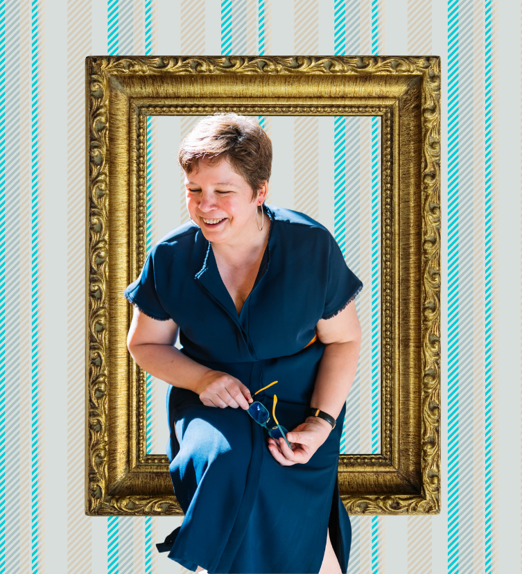 Hilde - oprichtster van BRAAZH - lachend en zittend binnen een grote, decoratieve gouden lijst tegen een achtergrond met blauwe en beige strepen.
