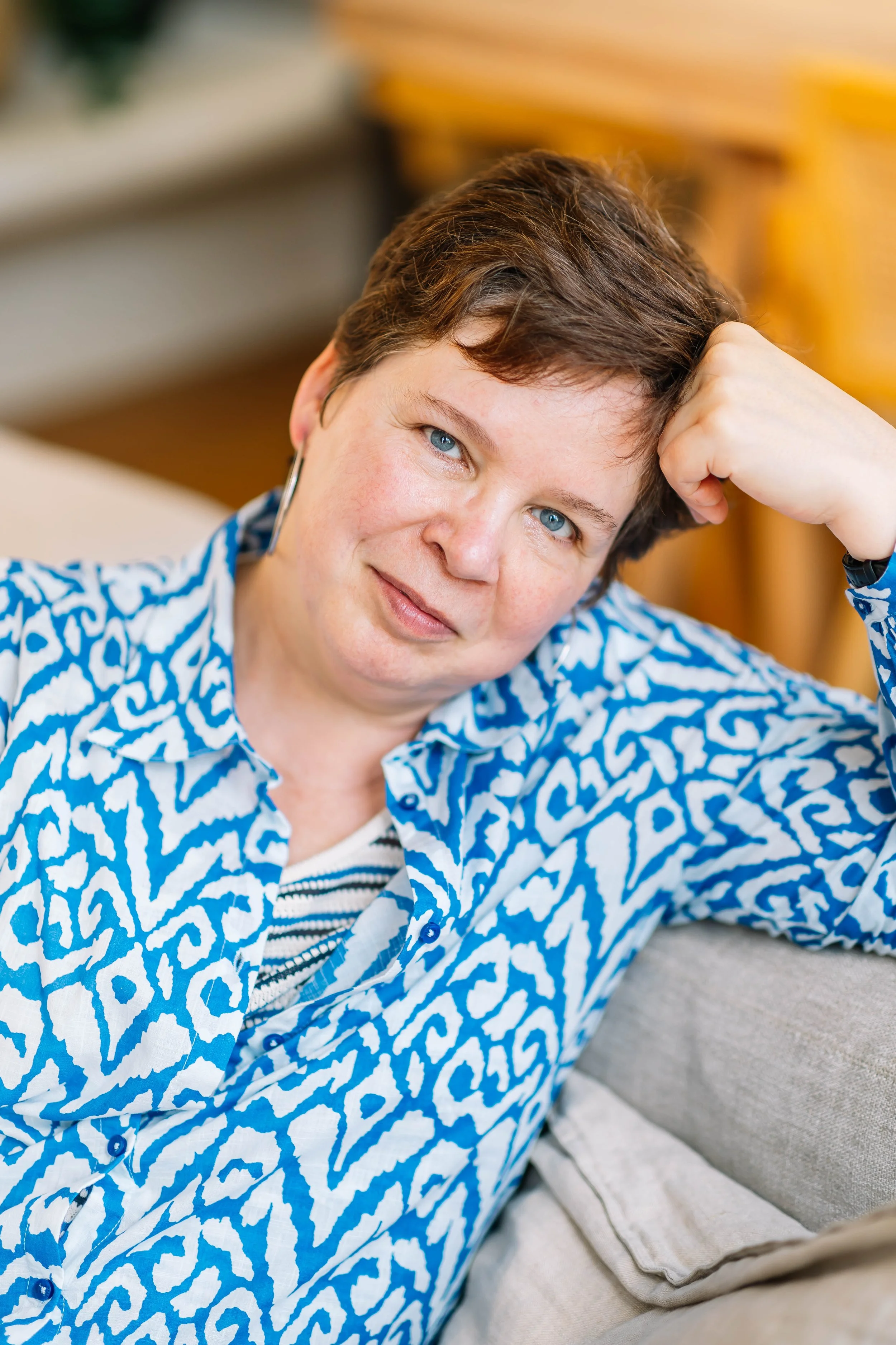 Hilde - oprichtster van 'BRAAZH': ze glimlacht terwijl ze op een bank zit in een woonkamer, ze is kalm en straalt rust uit.