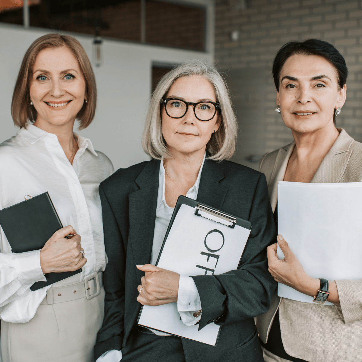 Drie zakenvrouwen in midlife met documenten voor een bedrijfsvergadering, serieus en professioneel. Ze staan er.