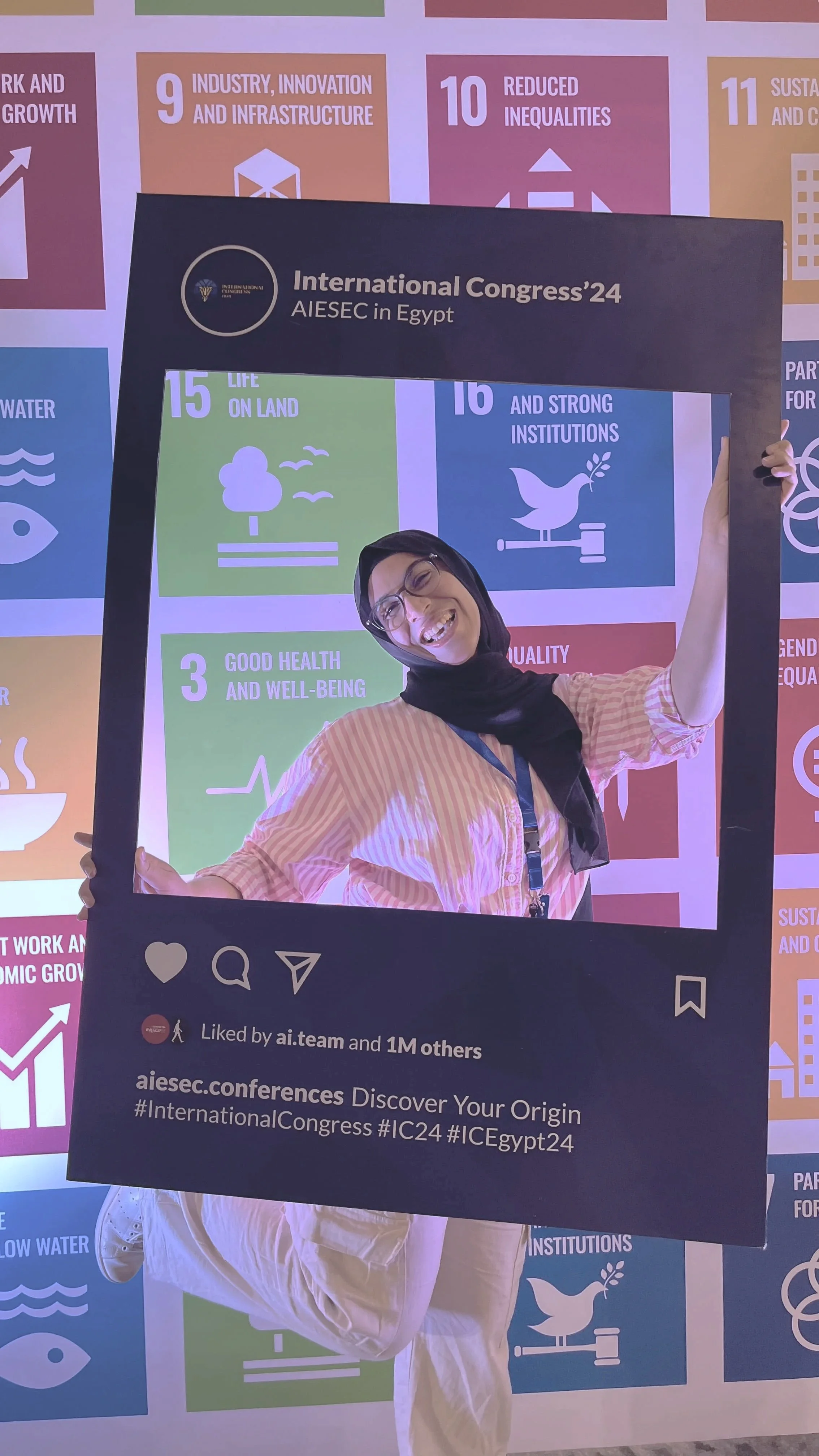 A person smiling and posing behind a large Instagram-style frame at the International Congress '24 in Egypt, with a background of colorful panels representing United Nations Sustainable Development Goals, including goals 3, 9, 10, 11, 15, and 16.