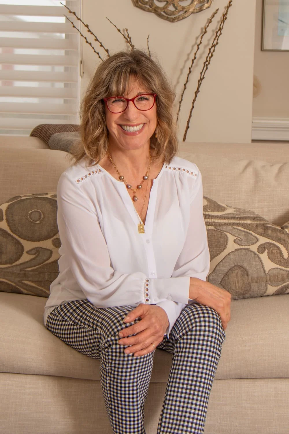 Andrea Nelson, licensed marriage and family therapist, smiling while seated on a beige sofa