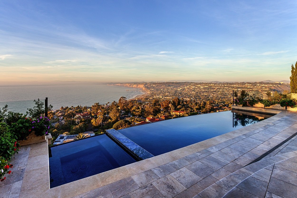 Infinity pool overlooking ocean and coastal landscape at sunset