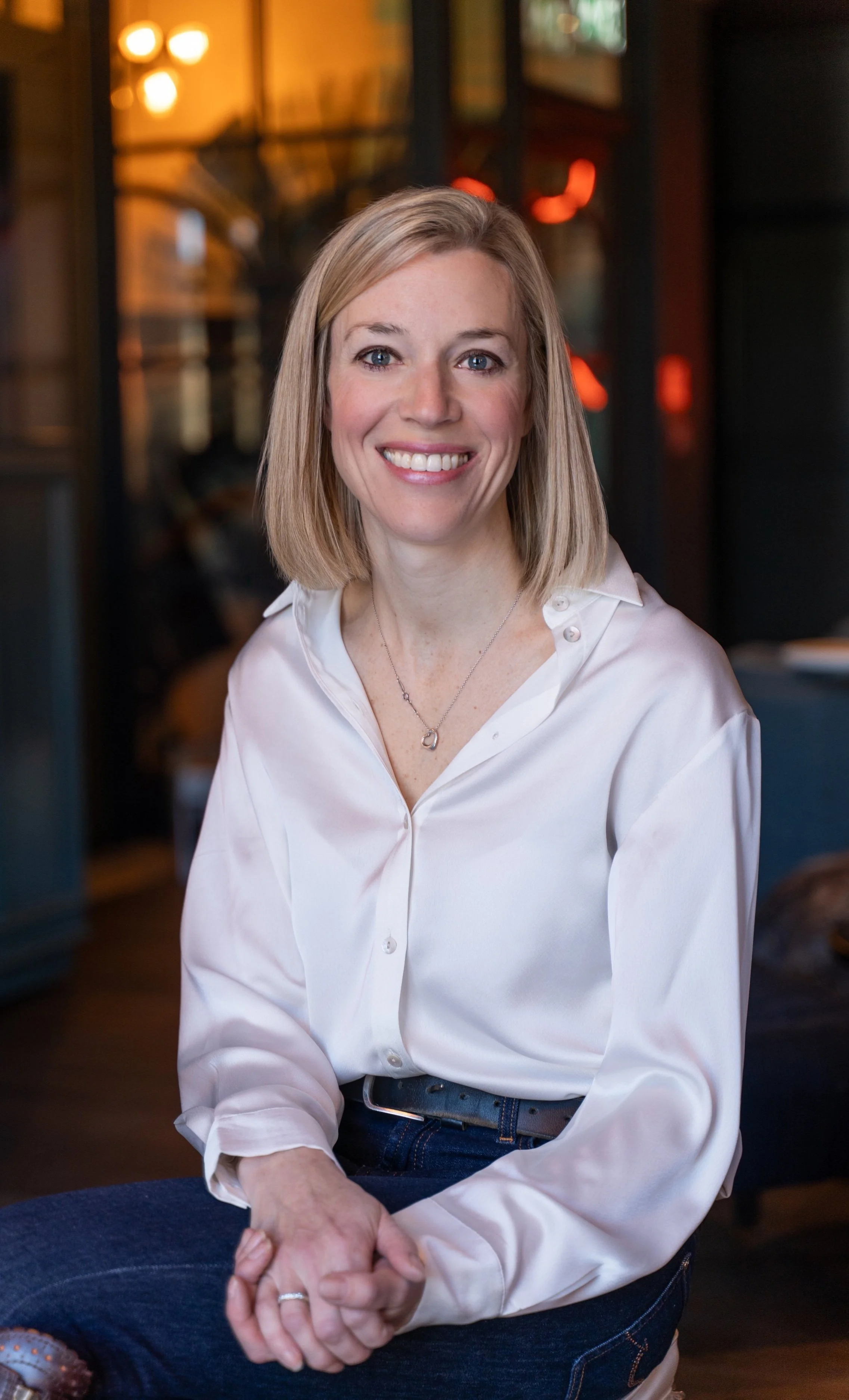 Woman in white blouse smiling indoors