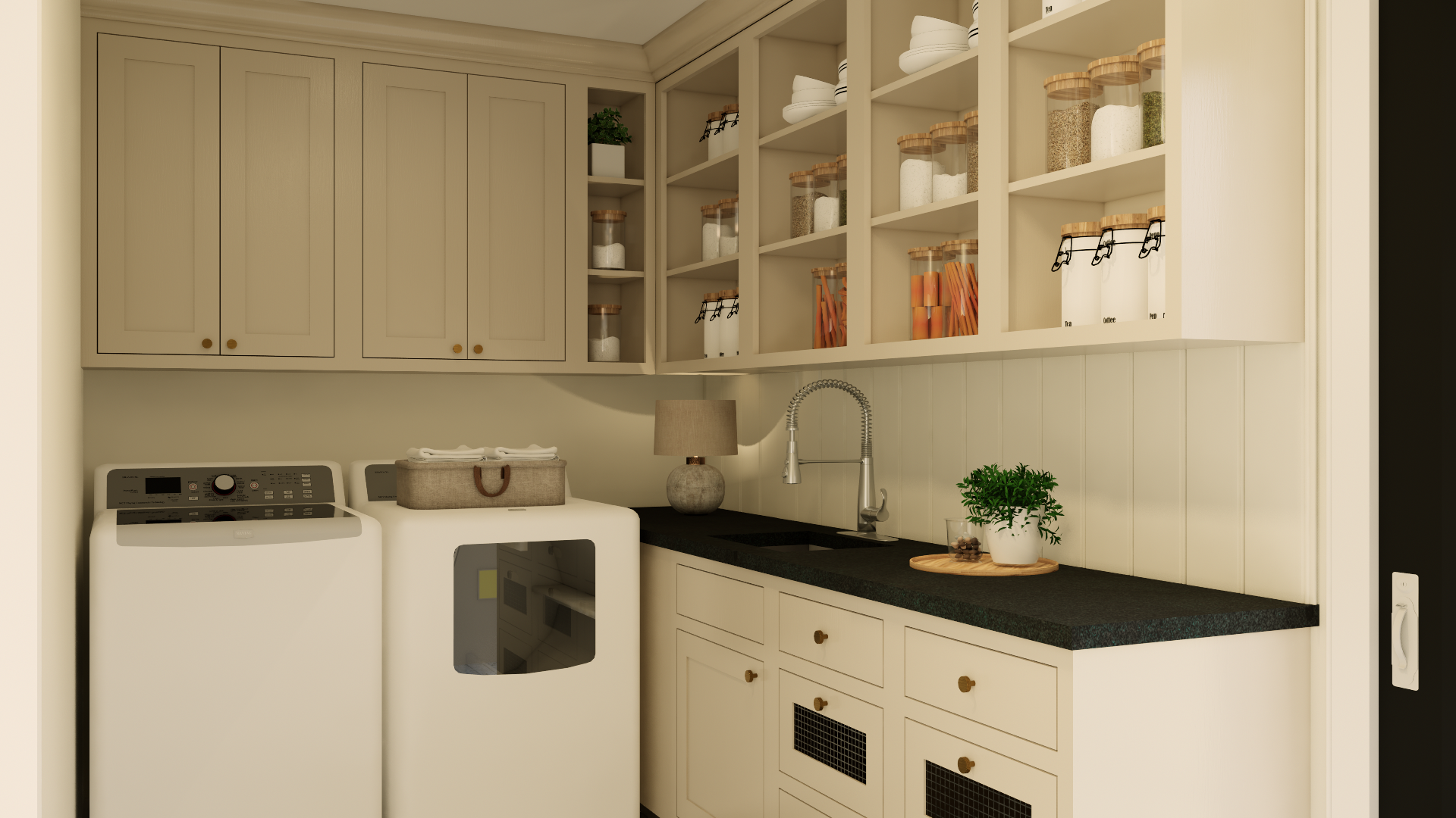 A laundry room with cream-colored cabinets, open shelves with jars of supplies, a washing machine, a dryer, a small lamp, a black countertop, a sink, a potted plant, and a few decorative items.