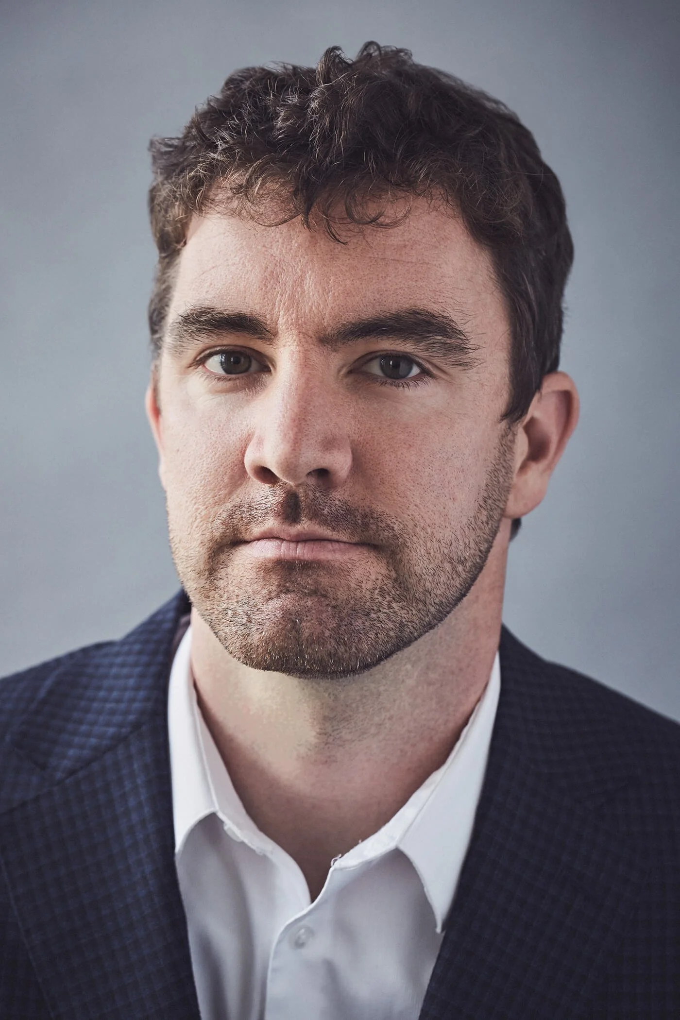 Man with short hair and beard in formal suit and white shirt