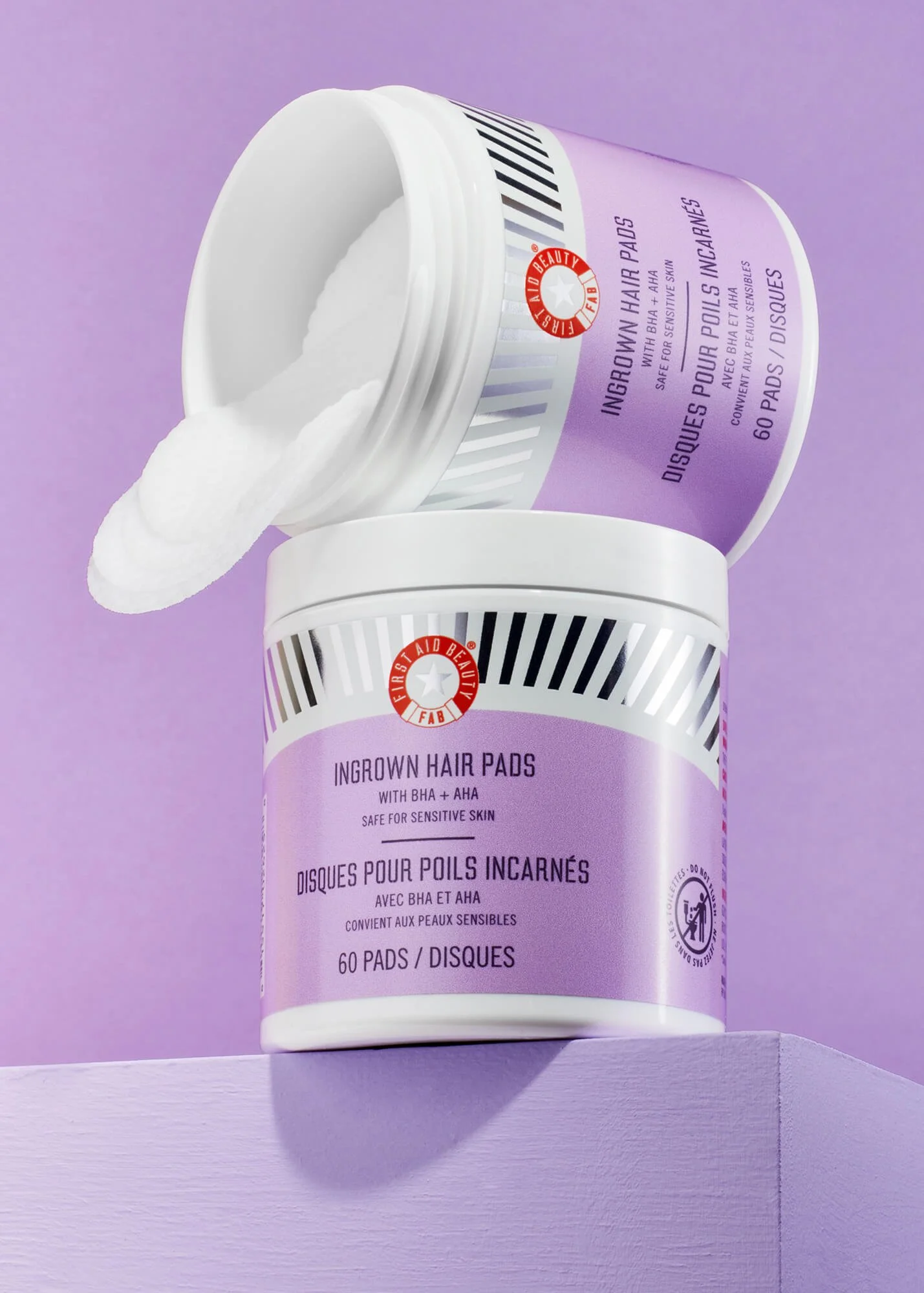 First Aid Beauty Ingrown Hair Pads with BHA and AHA, container on purple background.
