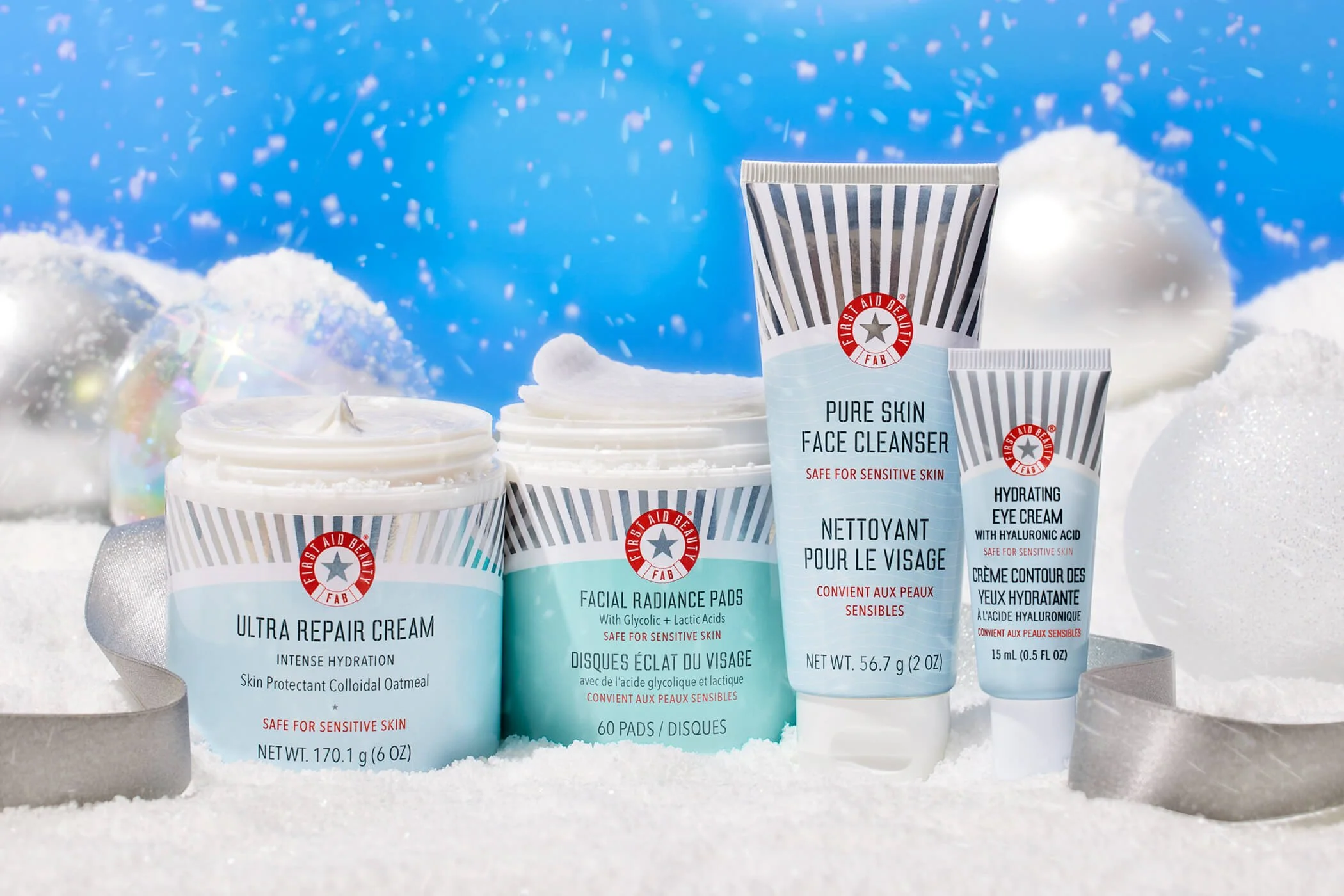 Skincare products on snowy background with blue sky, including Ultra Repair Cream, Facial Radiance Pads, Pure Skin Face Cleanser, and Hydrating Eye Cream.