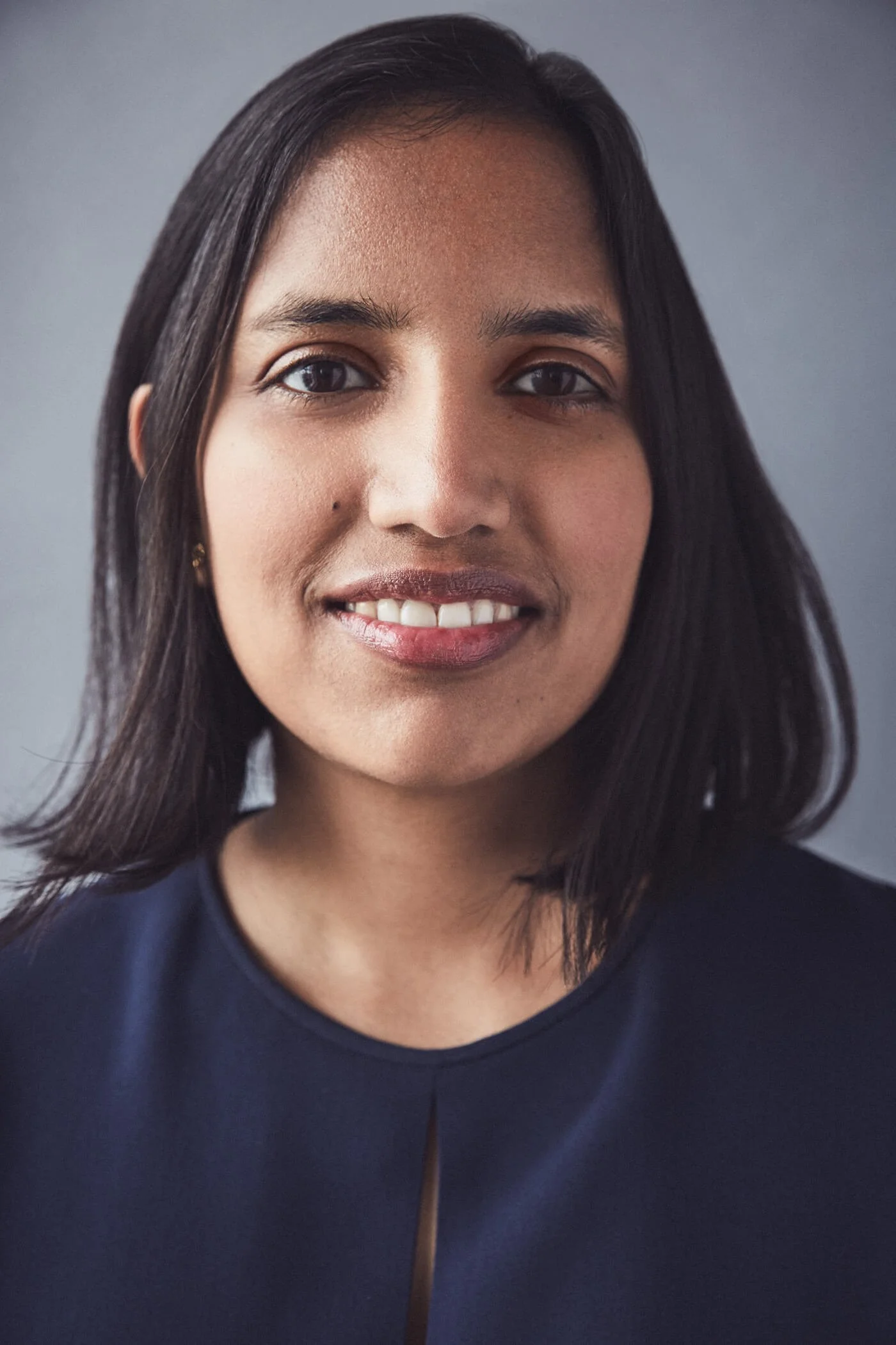 Portrait of a woman smiling with dark hair and a navy blue top.