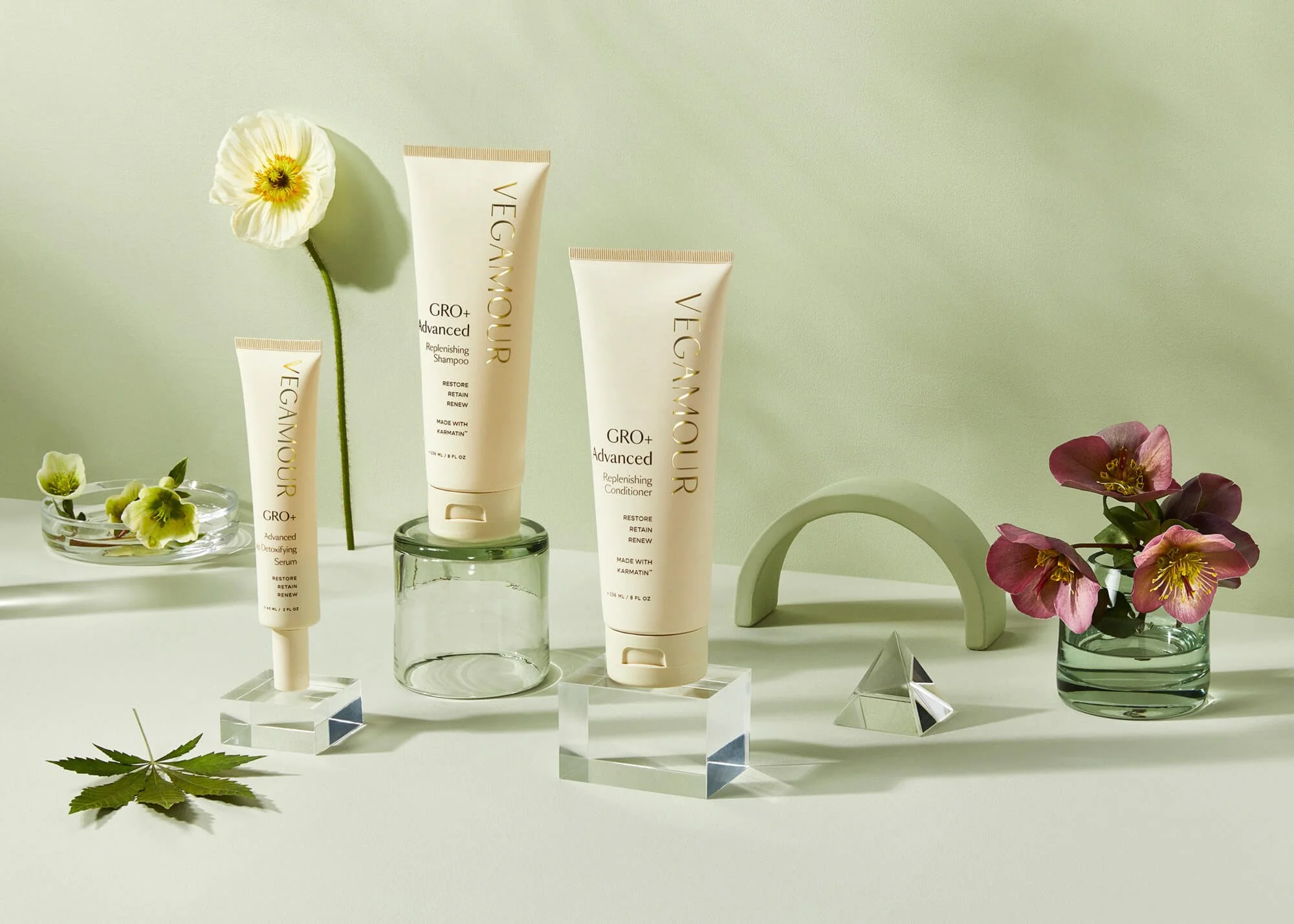 Vegan hair care products display with flowers and decorative glass pieces.
