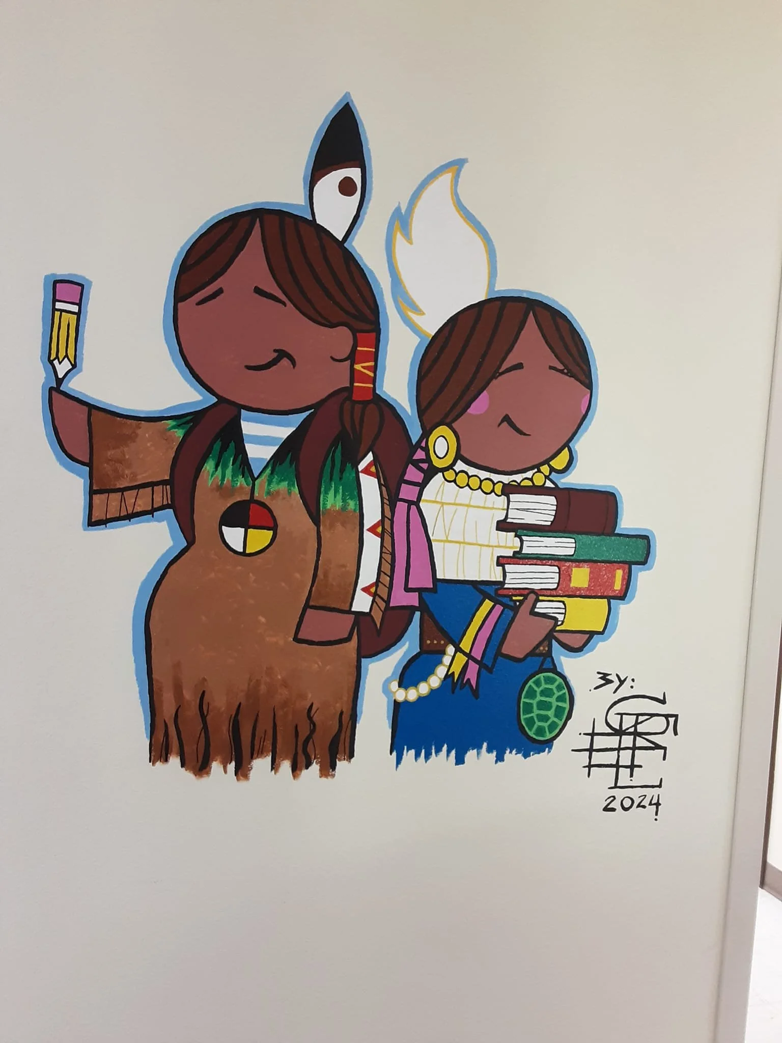 A colorful cartoon illustration of two female Indigenous characters with brown skin. The character on the left is holding a paintbrush, wearing a traditional dress and jewelry, with long brown hair and a feather in her hair. The character on the righ