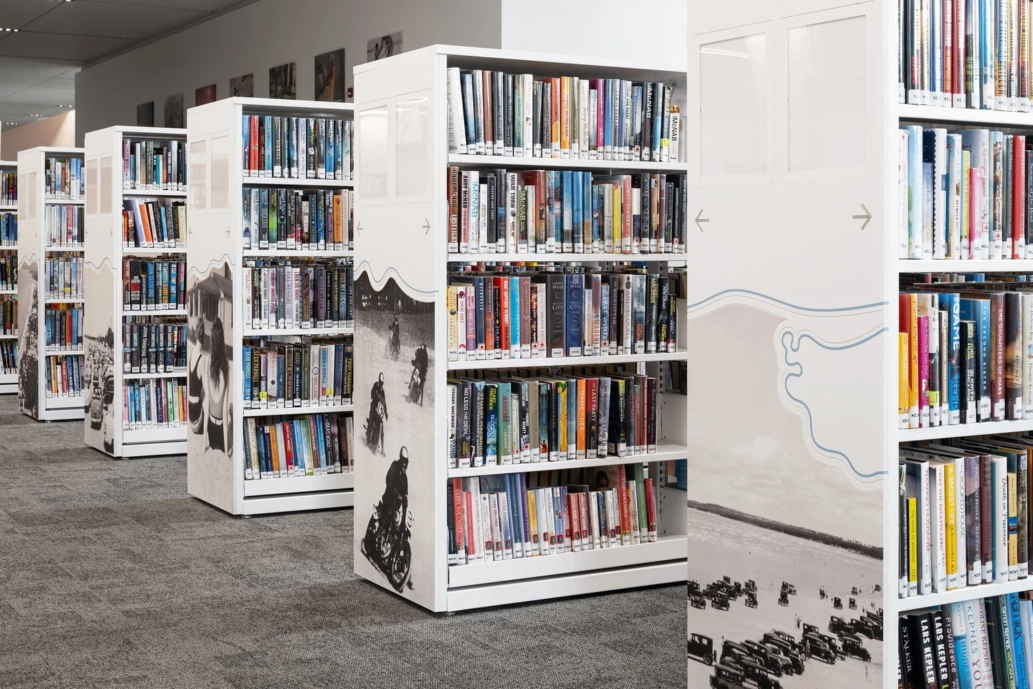 Shelf in a library with books and decorative black-and-white images on the side panels.