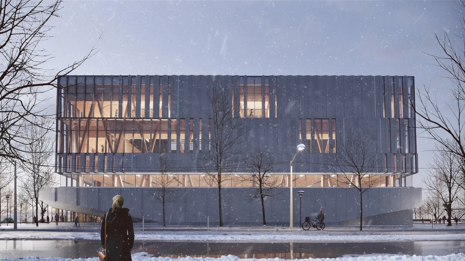 Modern multi-story building with large glass windows and wooden interior visible through the windows, set outdoors during winter with snow, leafless trees, and a person walking near a bicycle in the foreground under a cloudy sky.
