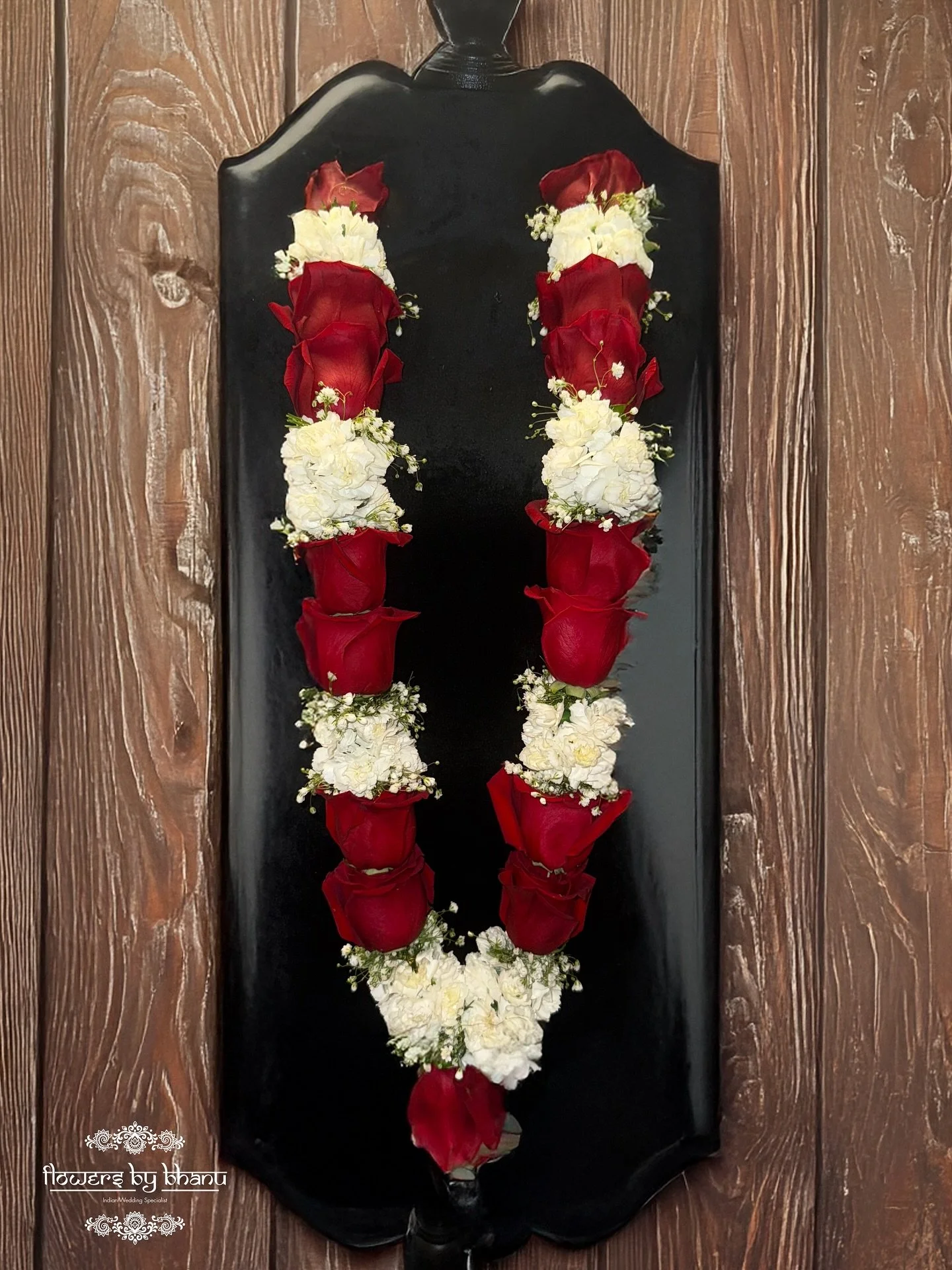 Elegant red roses paired with white mini carnations and baby&rsquo;s breath &mdash; a timeless garland symbolizing love, purity, and grace. 🌹🤍 Perfect for weddings and special celebrations.