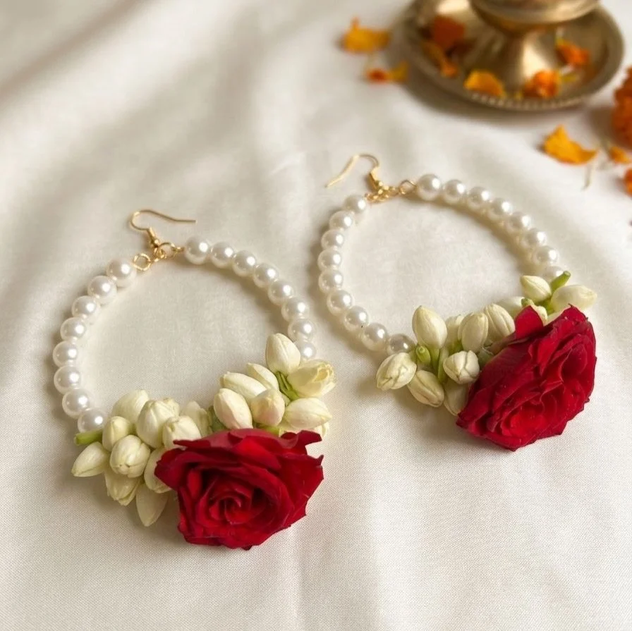 Handcrafted jasmine buds paired with a bold rose, finished with delicate pearl hoops &mdash; a timeless blend of tradition and grace.