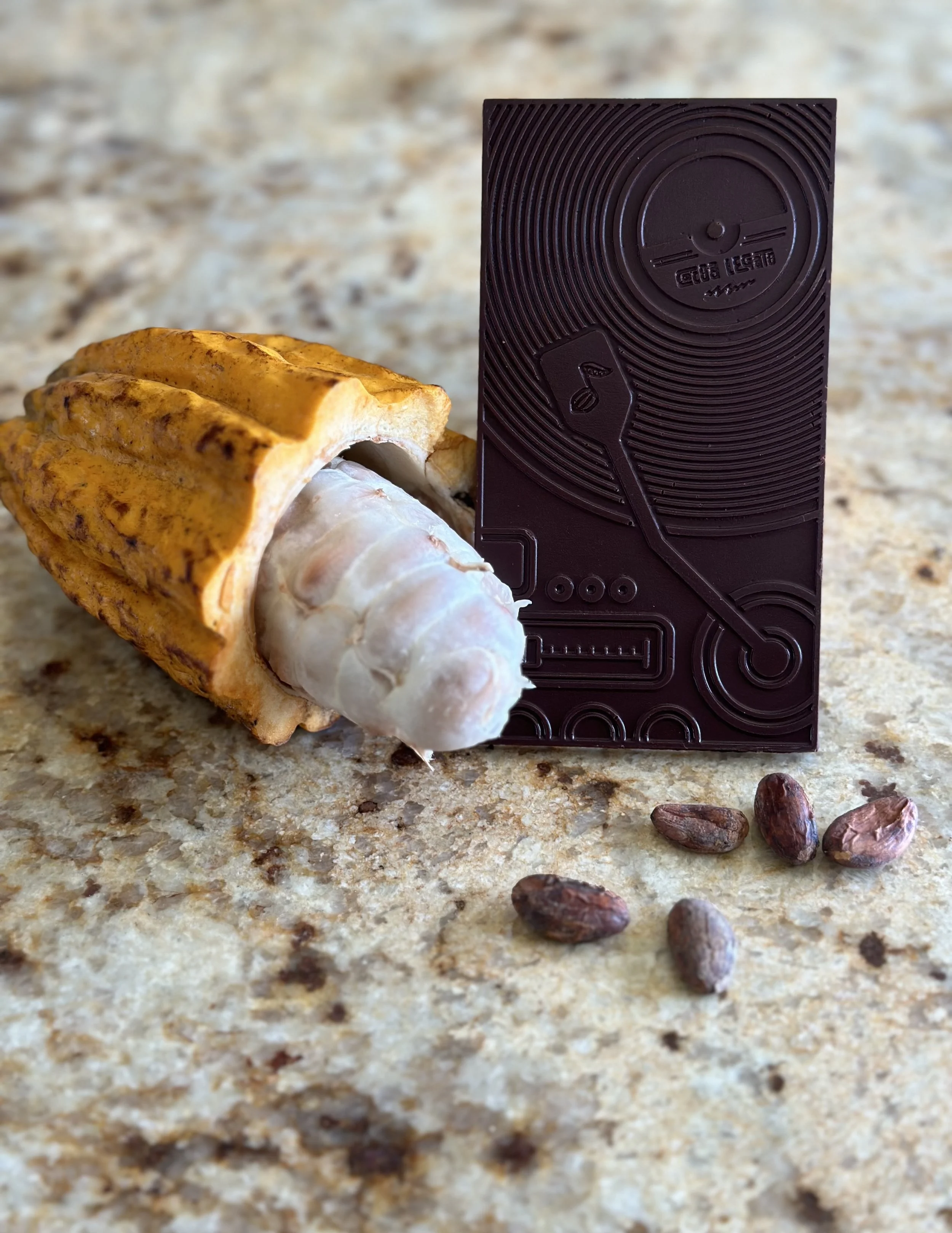 **Alt Text:**   A ripe, orange-brown cacao pod resting on a pile of dried cacao beans, displayed on a rustic wooden surface. The pod has a ridged texture, and the beans are dark brown with a slightly rough appearance.
