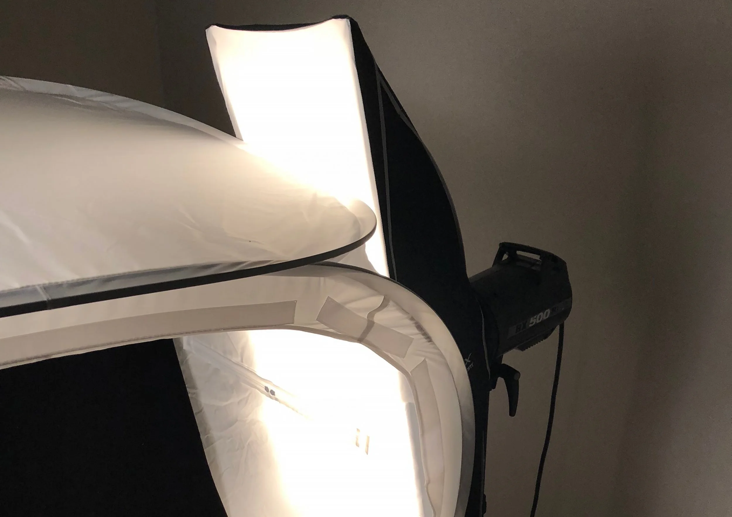 The light on the right side of the light tent is the fill light.  Fill lights are used to open up shadows, but this light for this setup is also doing some heavy lifting.  It isn't gridded because it is needed for broader light coverage of the subjec