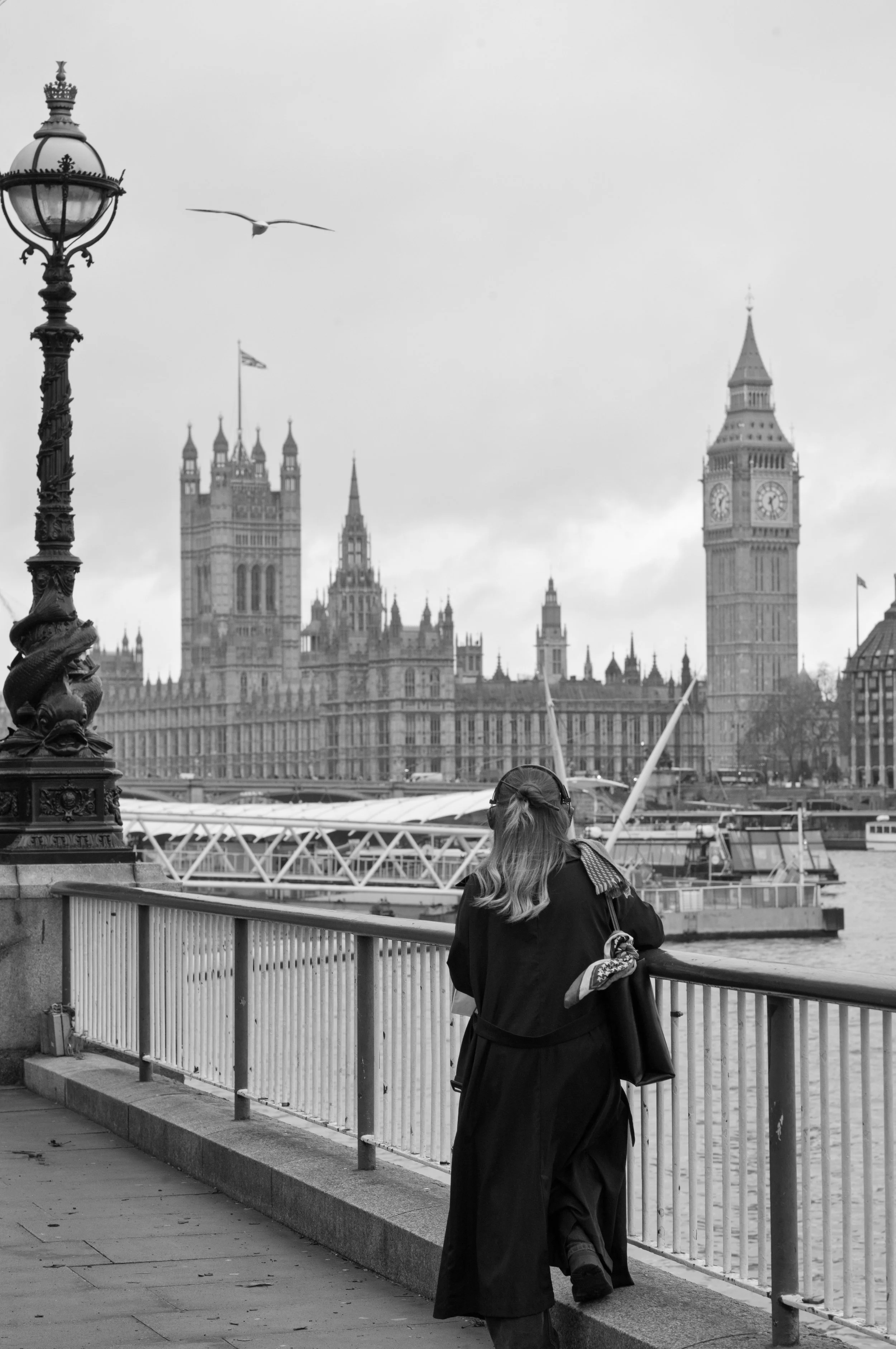 Woman taking in Big Ben and Westminster Abbey from the shore of the Thames