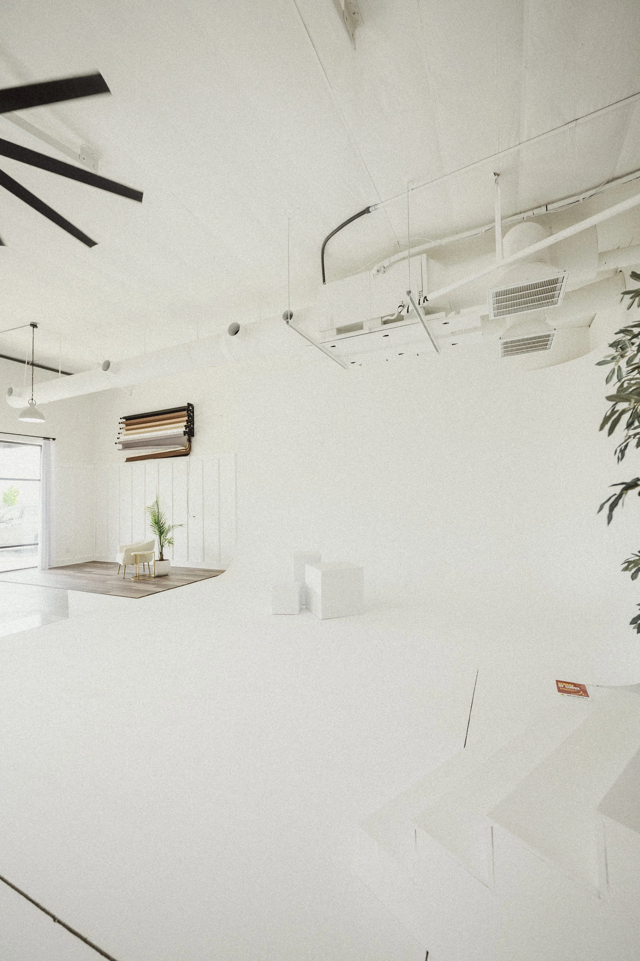Empty white photography studio with a seamless white backdrop, studio equipment, and minimal furniture.