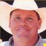 A man wearing a white cowboy hat, smiling at the camera.