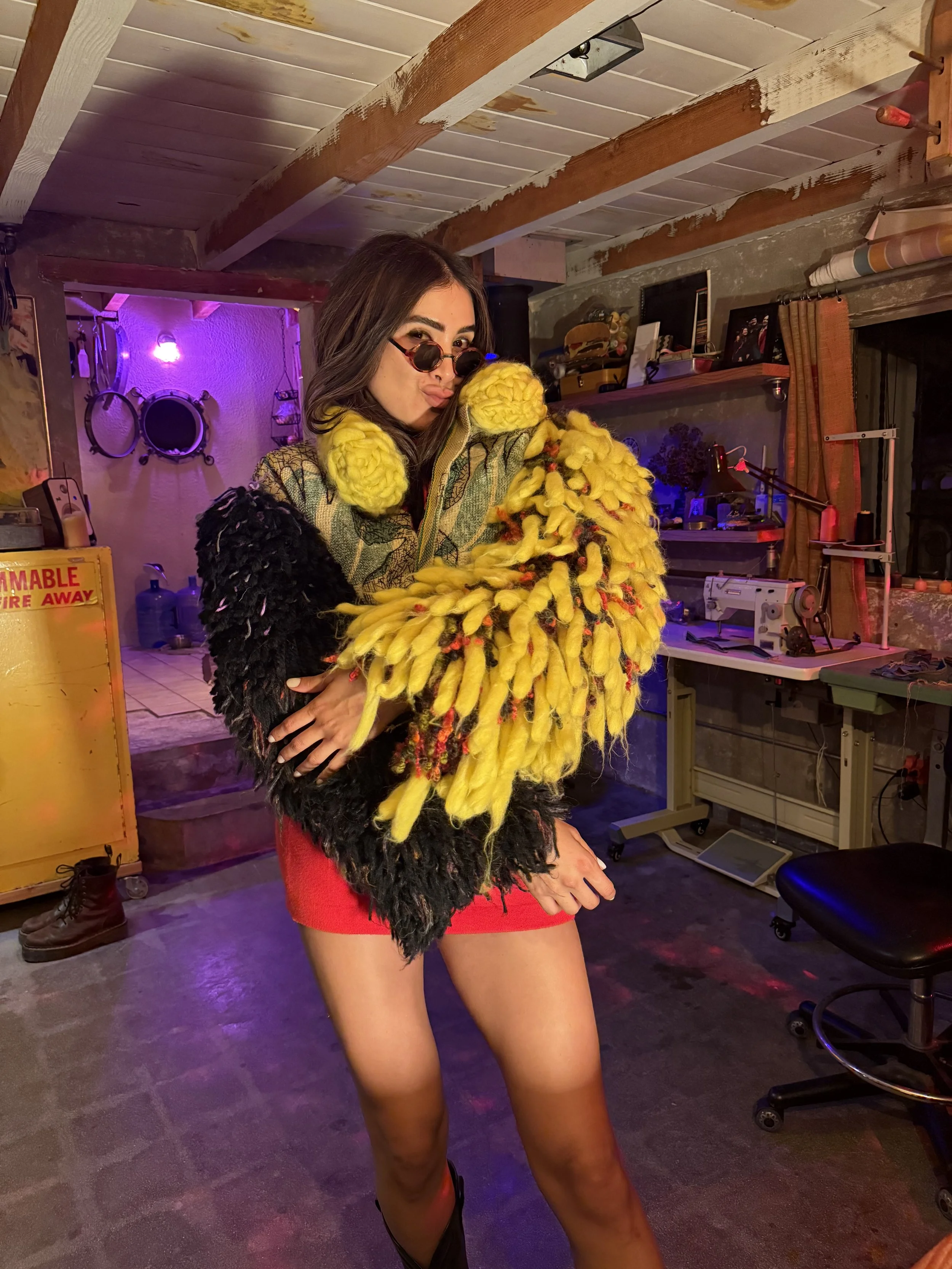 A model wearing a sculptural black and yellow shaggy TIC jacket inside Addison Stonestreet’s studio.