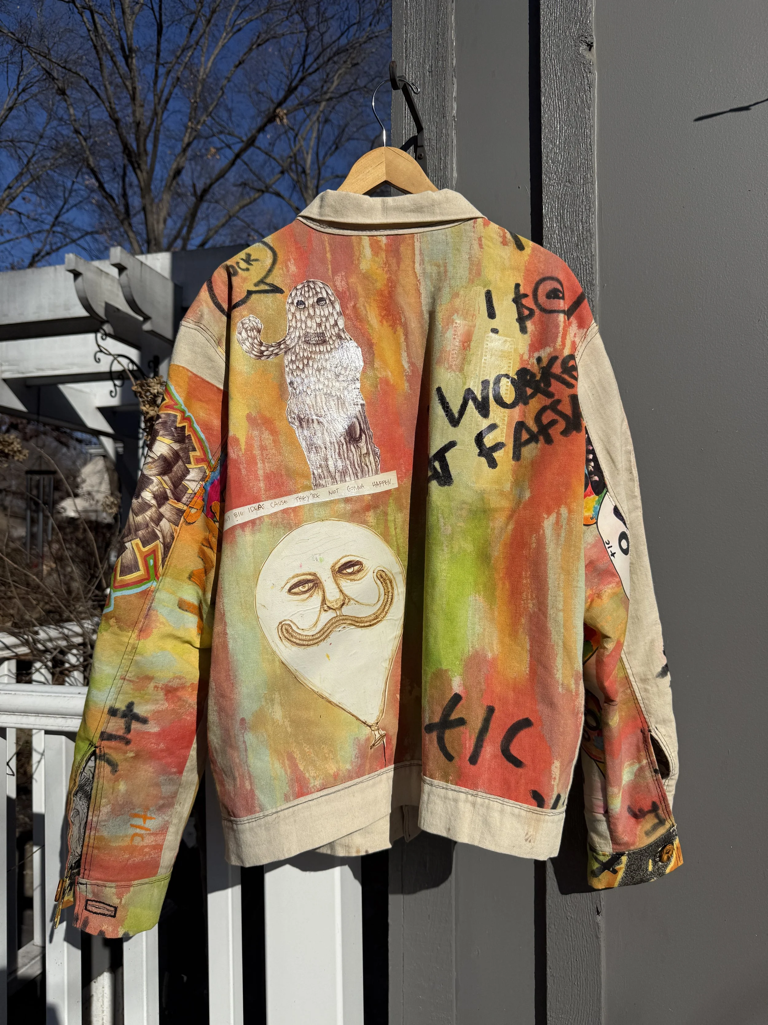 Back view of a colorful hand-painted TIC jacket featuring abstract figures, handwritten text, layered imagery, and one-of-a-kind surface details.